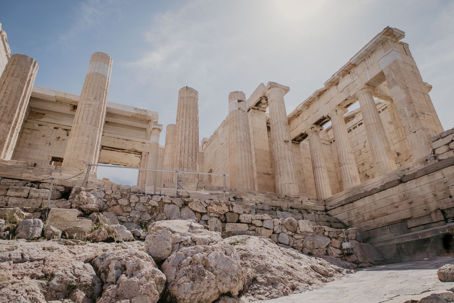 Ancient Greek ruins with towering marble columns against a bright blue sky.