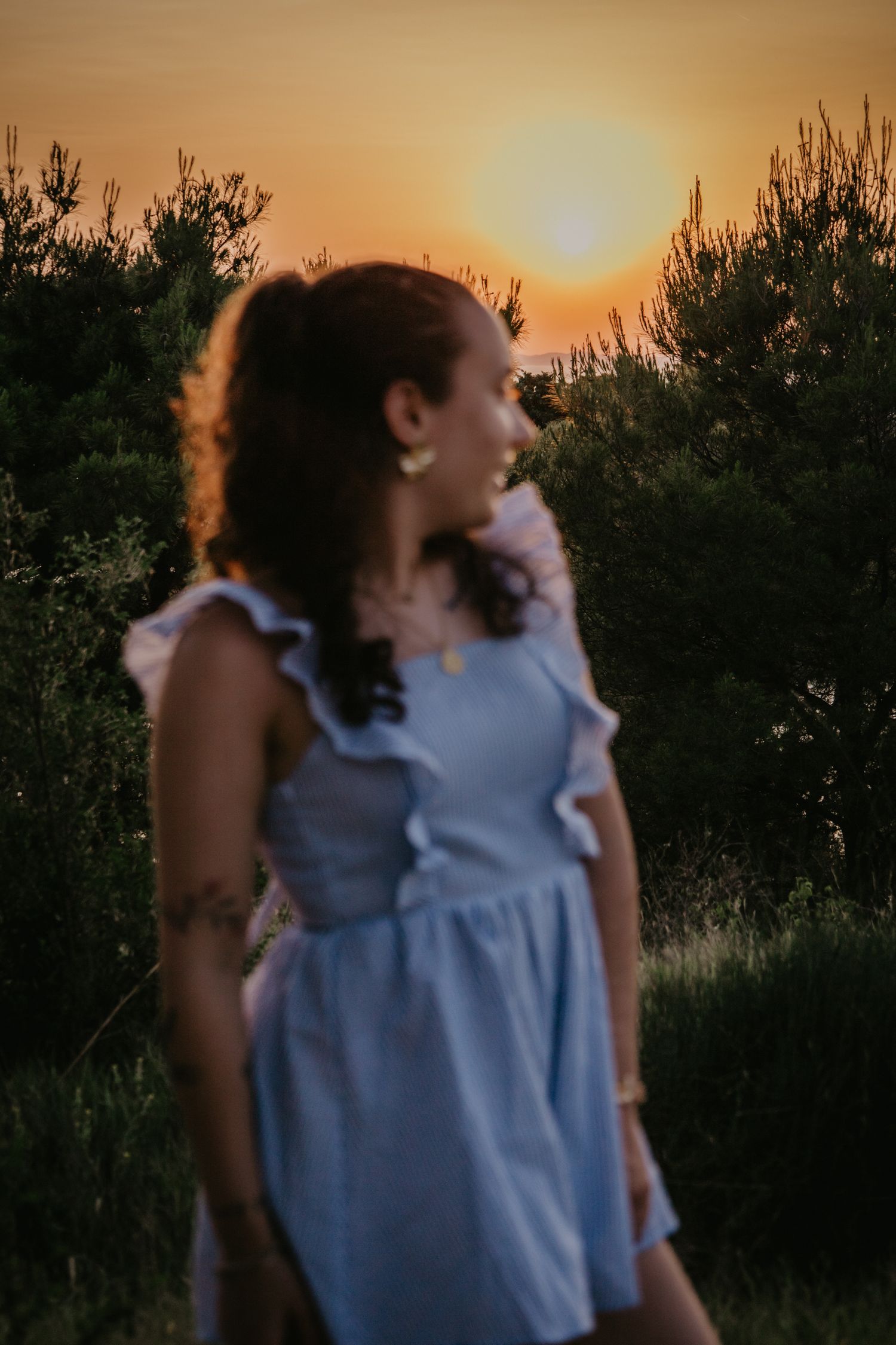 Artistic sunset portrait in a blue sleeveless top with ruffle details.