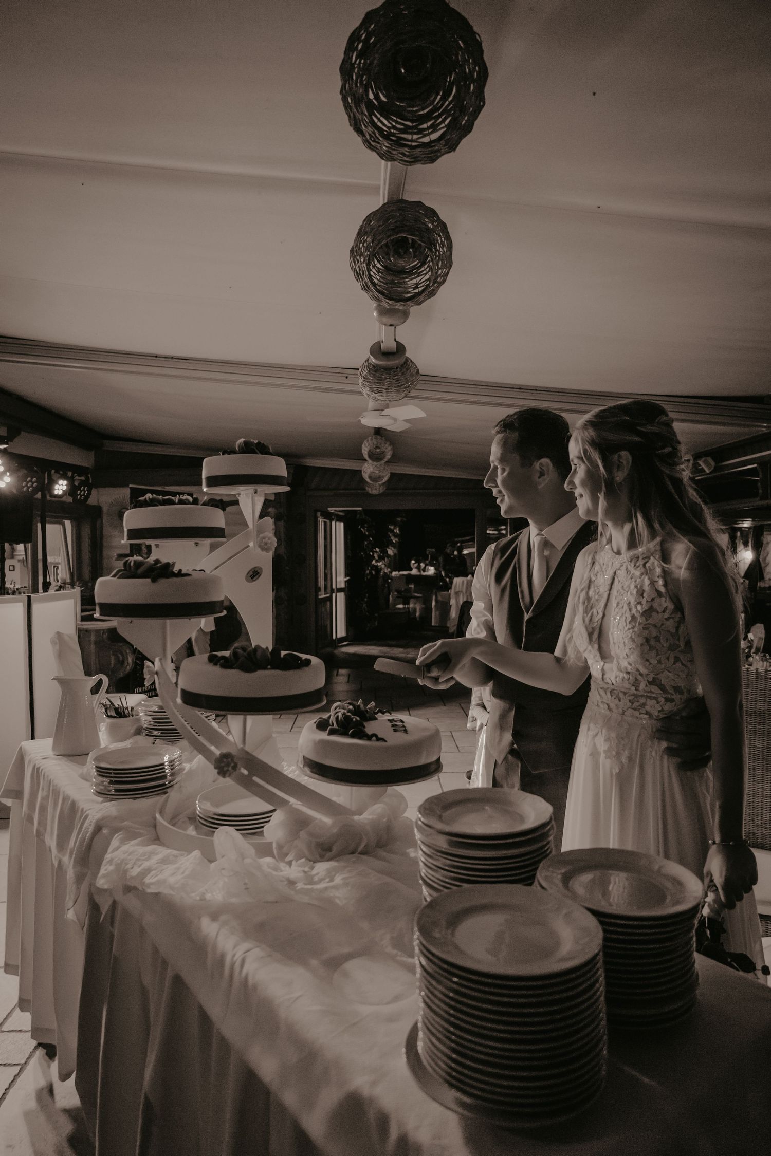 Wedding couple looking at their tiered cake display with stacked plates.