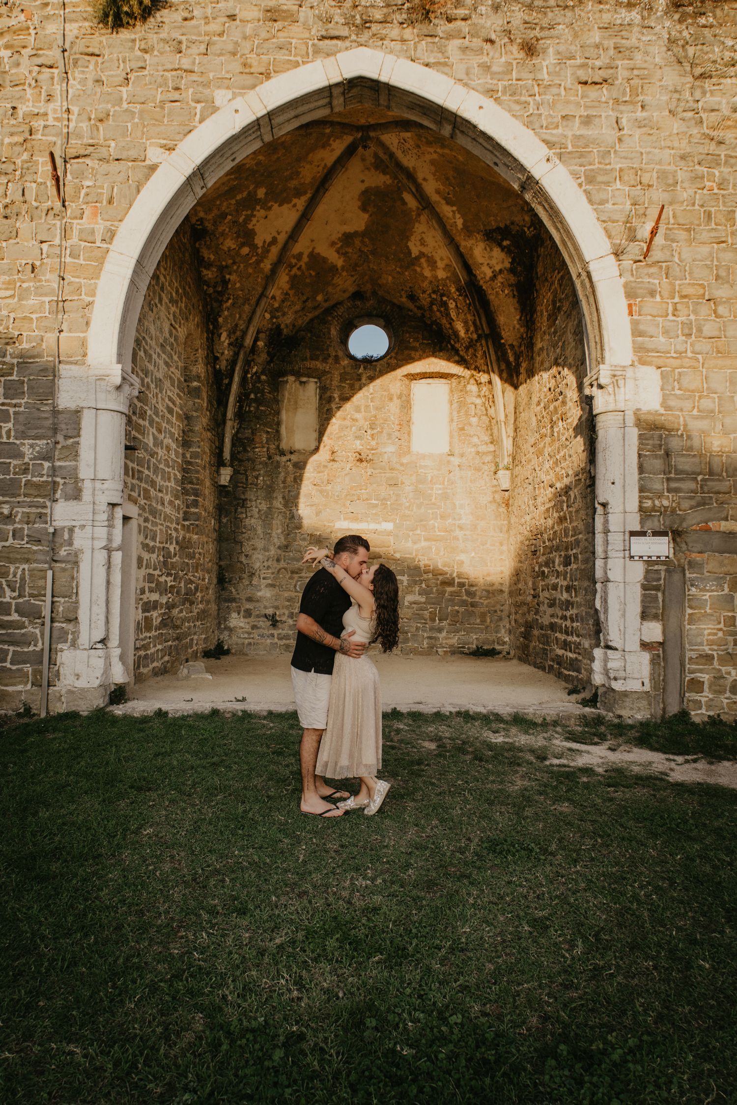 Romantic moment captured under stone archways of historic building.
