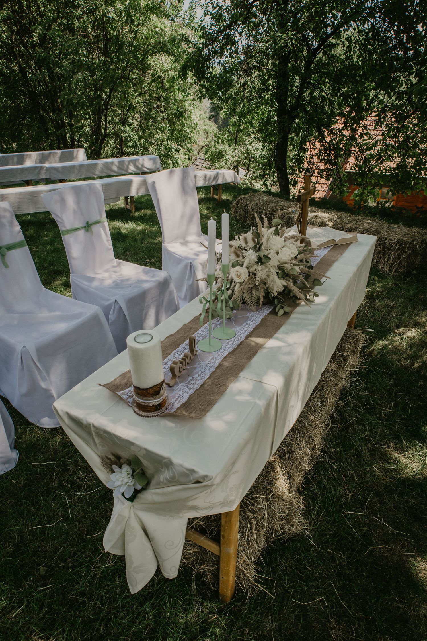 Elegant outdoor wedding reception table with white linen, candles, and floral centerpiece set in a lush garden.