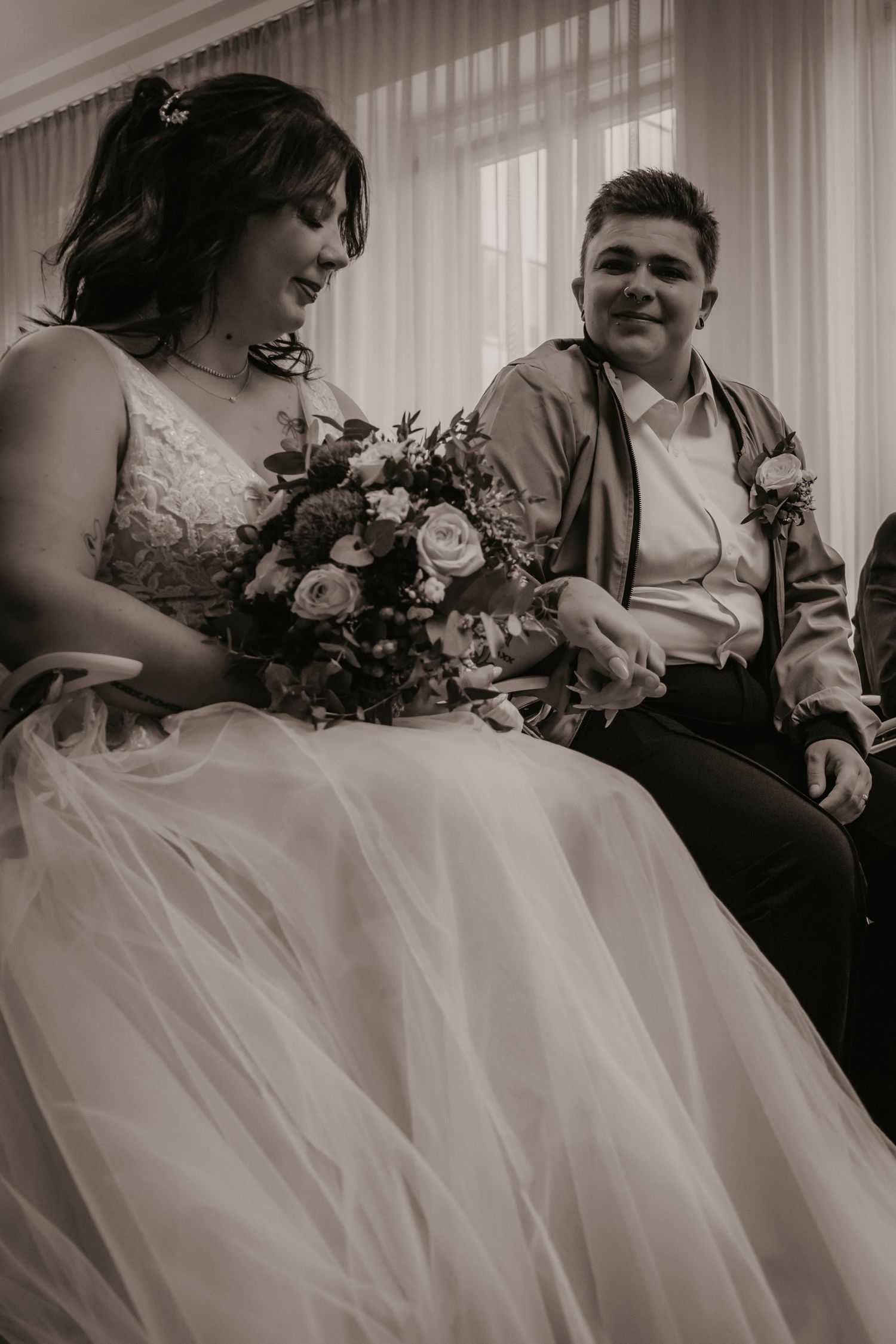 Wedding couple seated together with bride holding a beautiful bouquet of roses.