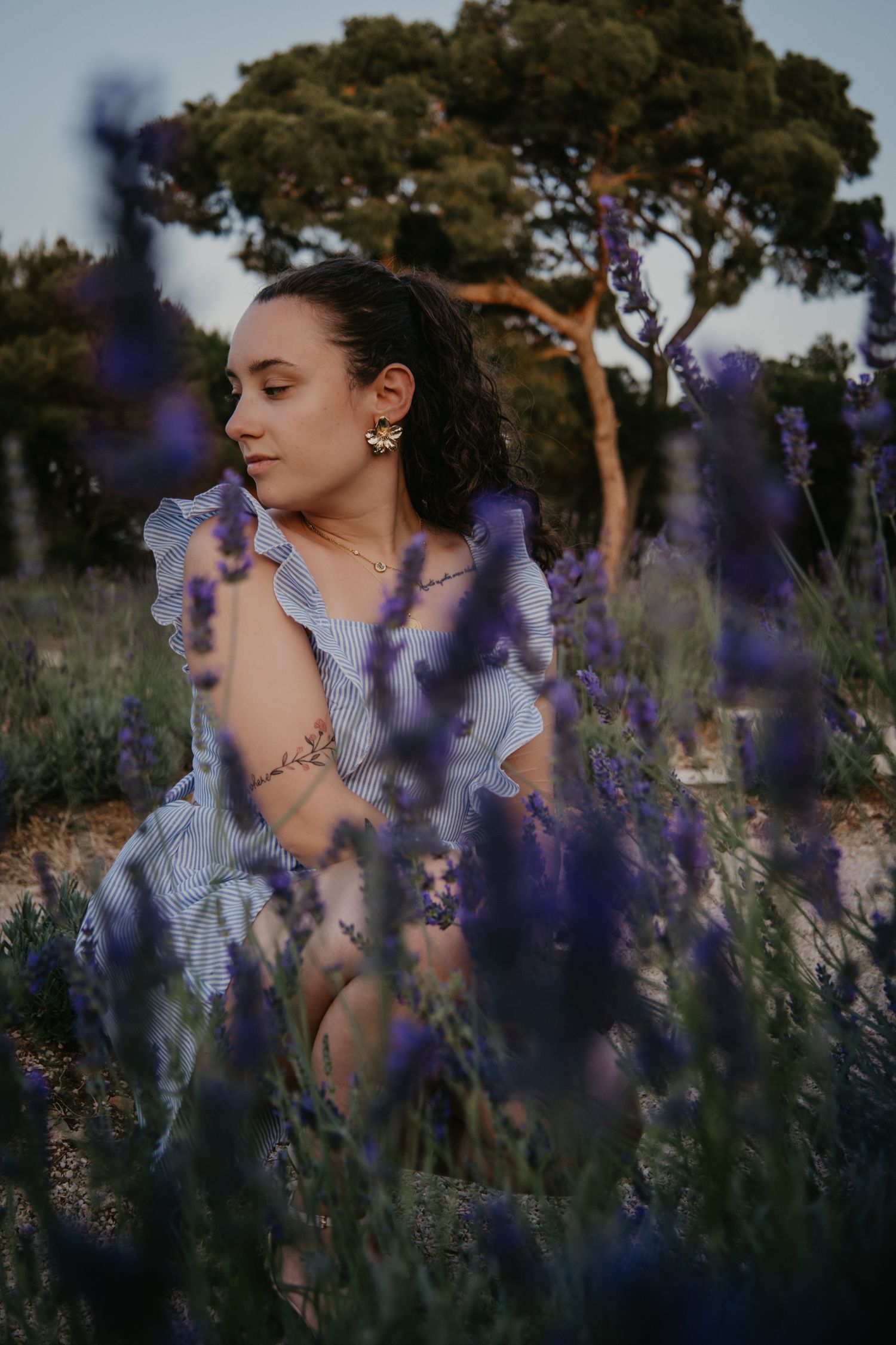 Artistic portrait through purple lavender flowers in golden evening light.