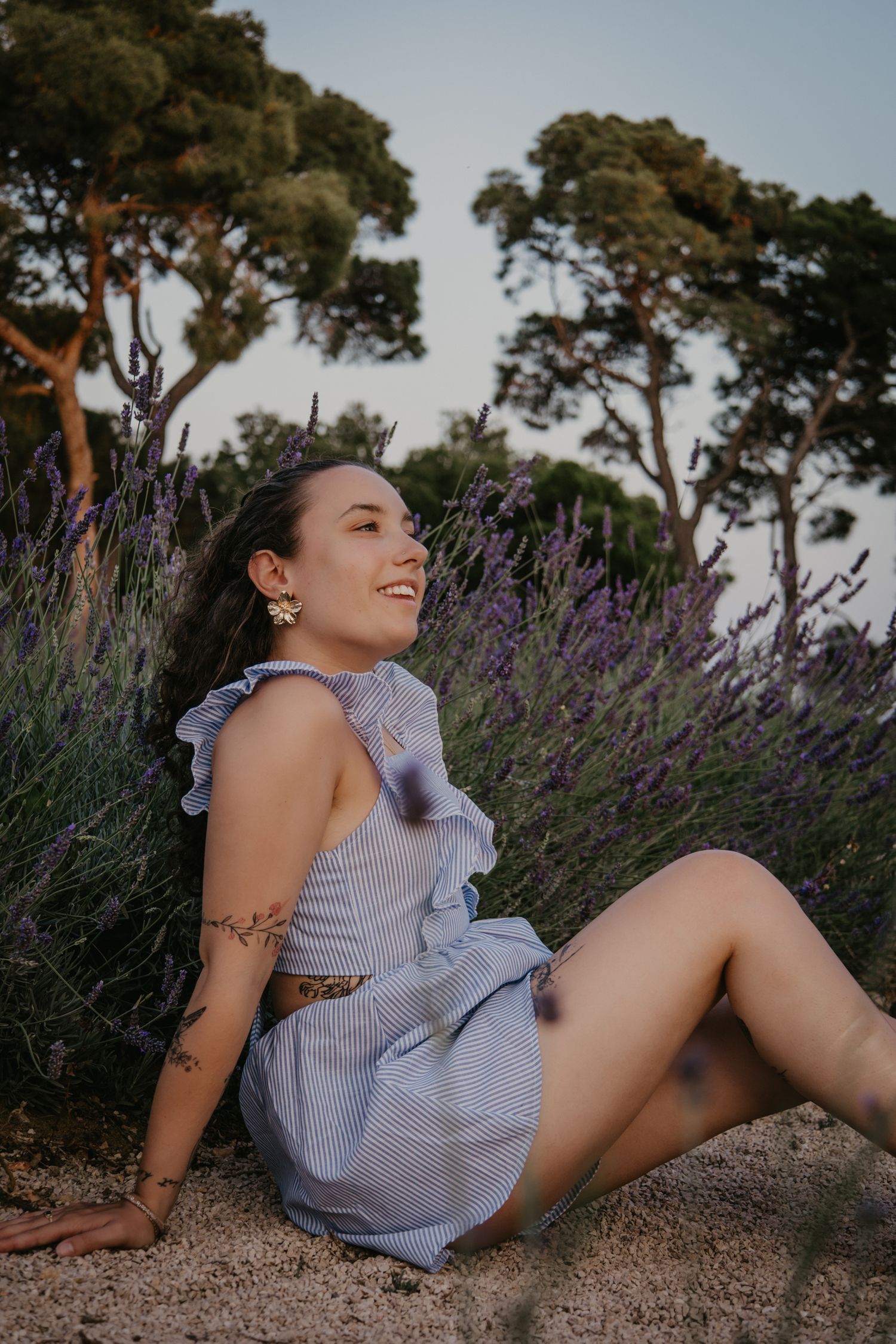 Relaxed summer portraits in blue striped outfit amid lavender and trees.
