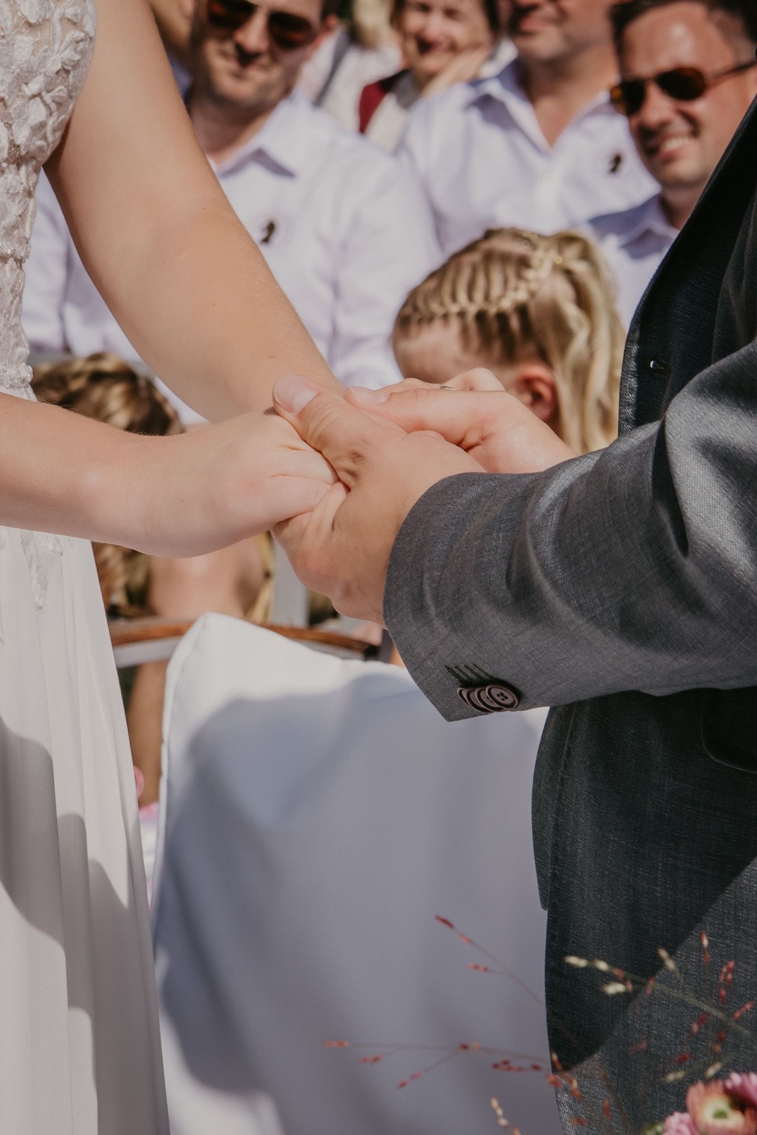 Hands joined together during an outdoor wedding ceremony.