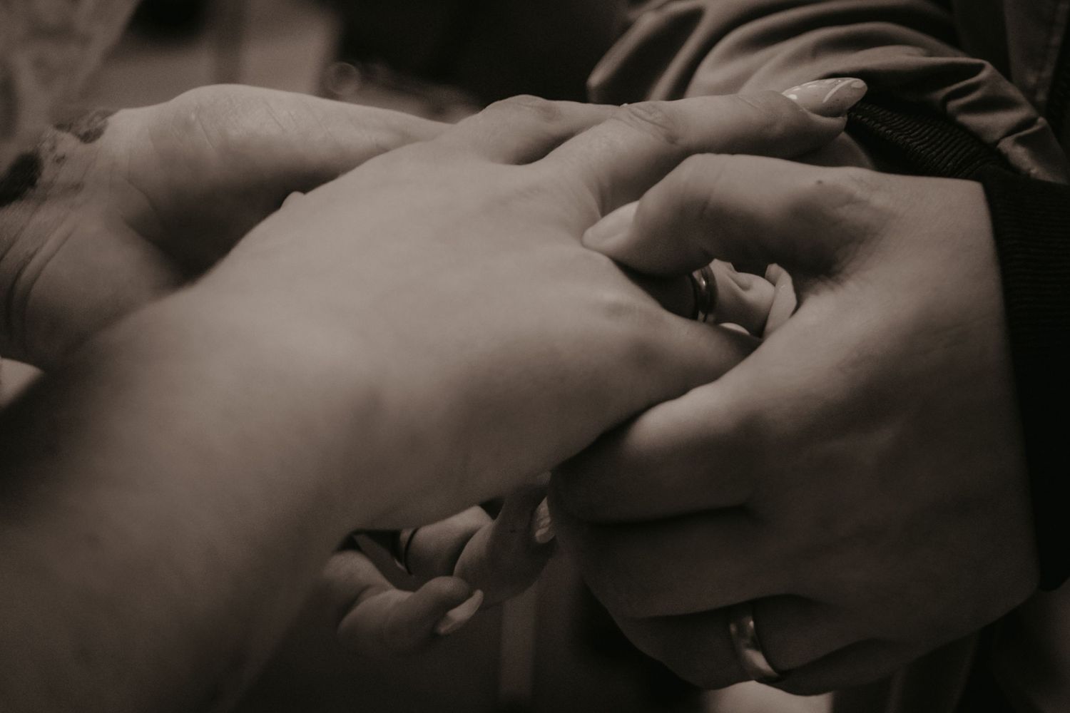 Artistic black and white close-up of hands exchanging wedding rings.