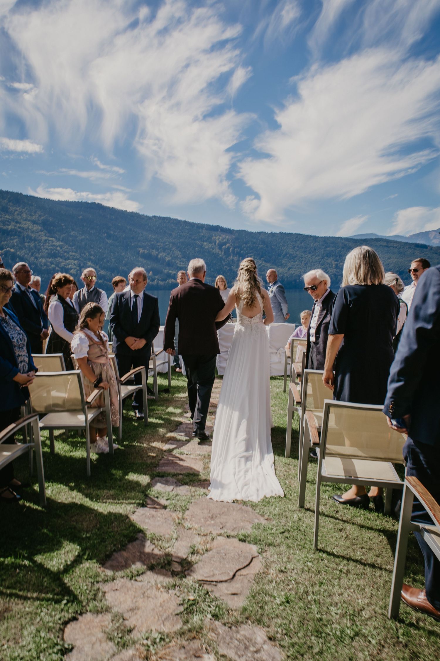 Outdoor wedding ceremony setup with chairs and mountain backdrop under blue skies.