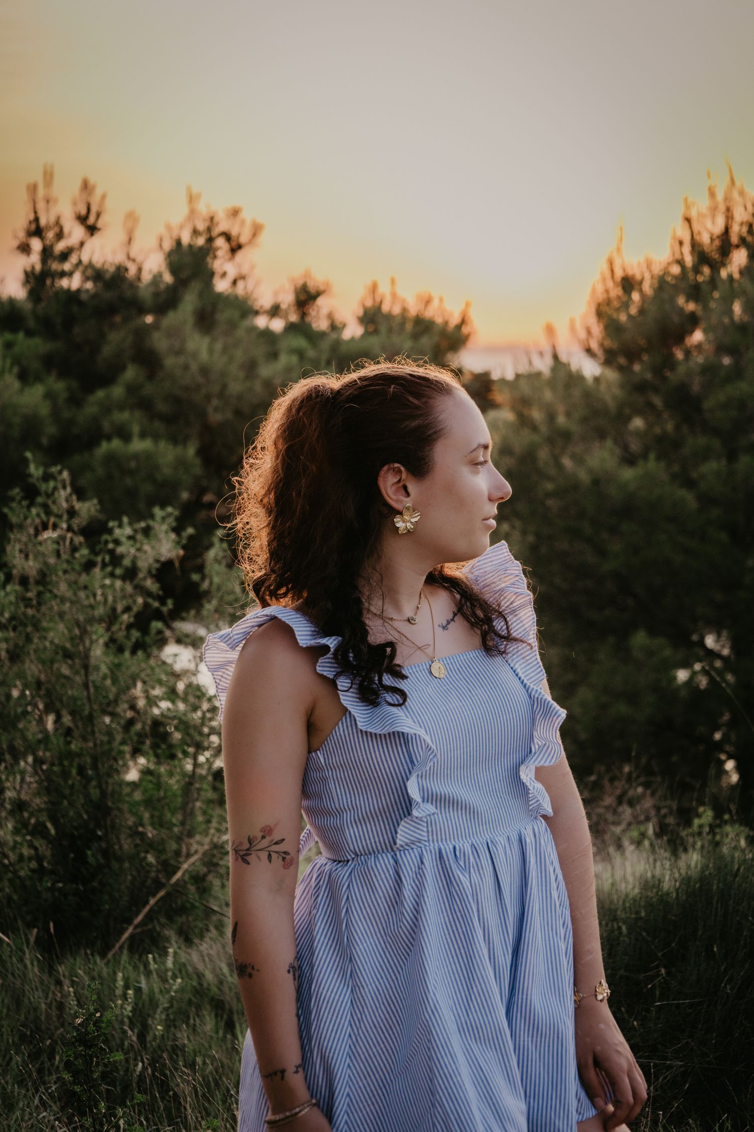 Natural outdoor portrait featuring a blue striped summer top with white ruffles.