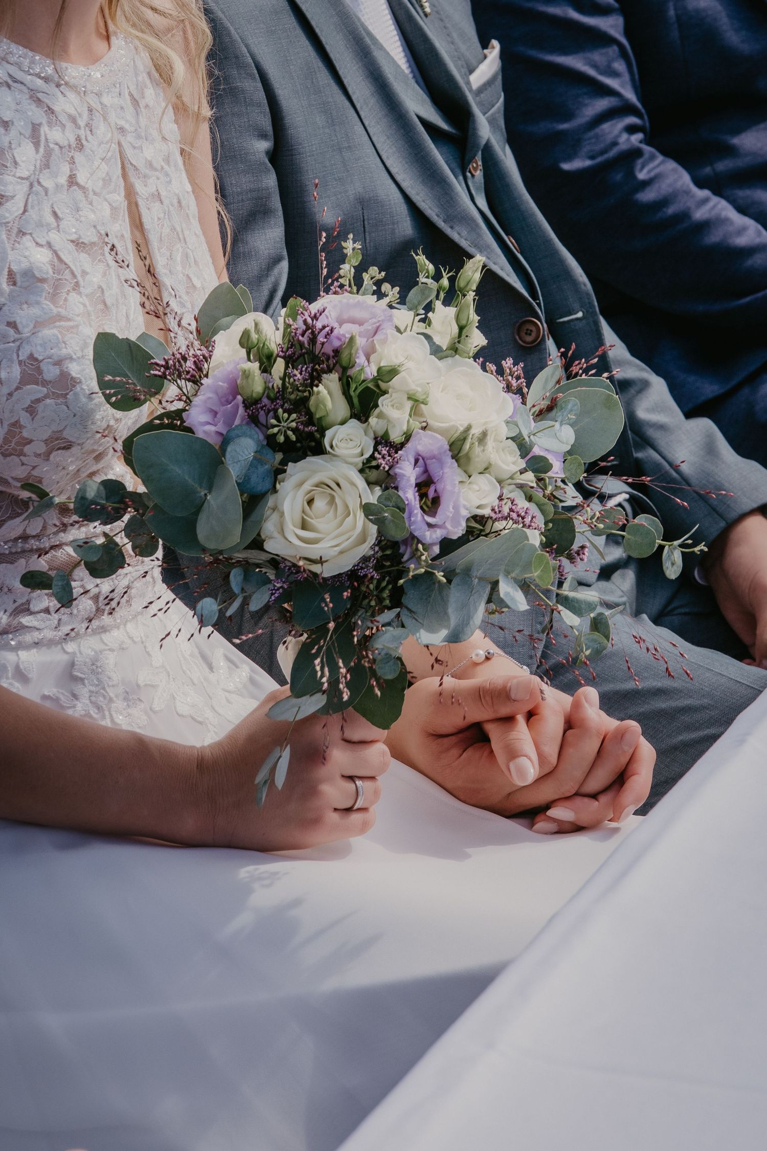 Wedding ceremony detail showing hands signing documents next to elegant floral arrangement.