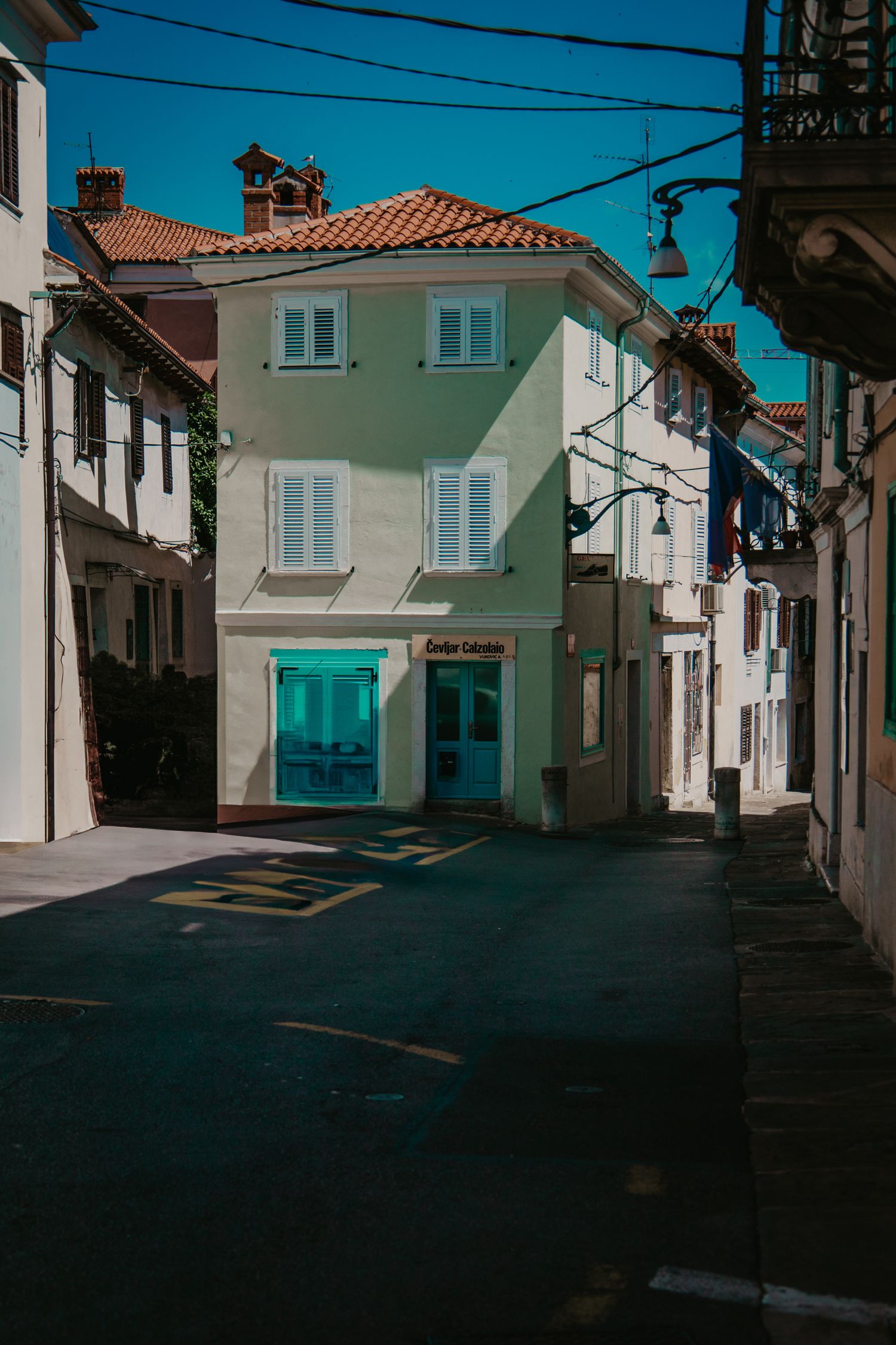 Quiet Mediterranean street with white buildings and power lines in dramatic lighting.