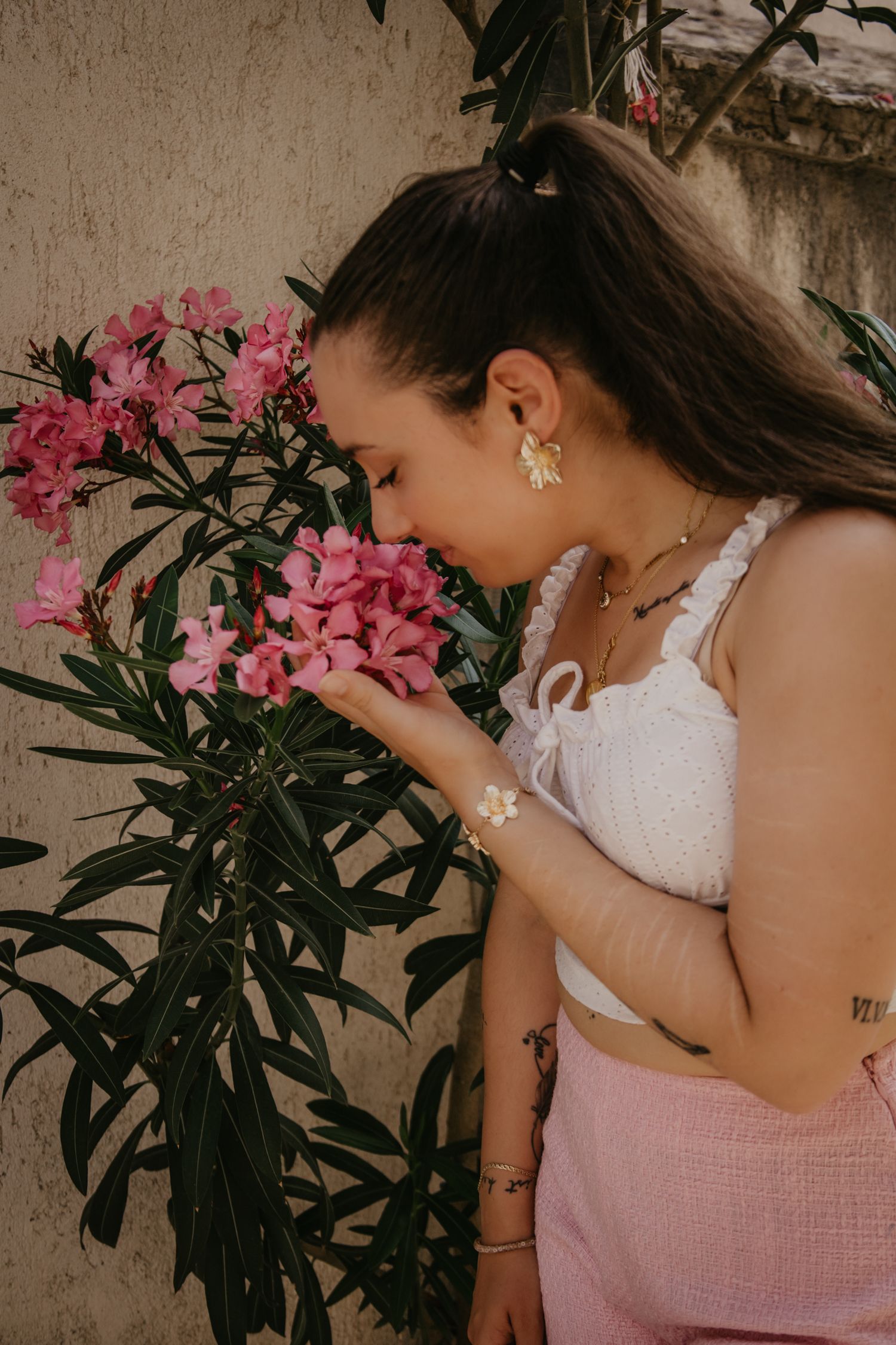 Artistic portrait series with pink oleander flowers and white summer attire.