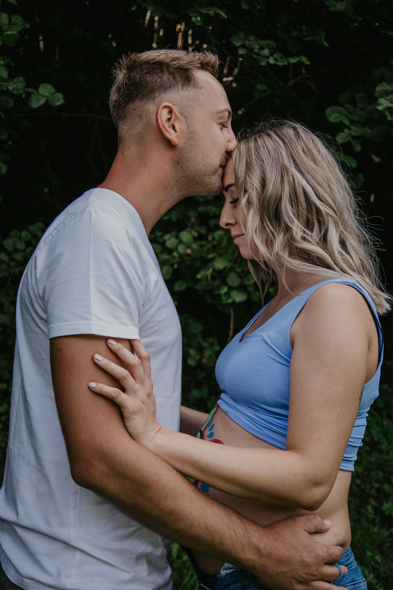 Romantic maternity photoshoot poses captured in an outdoor woodland setting.