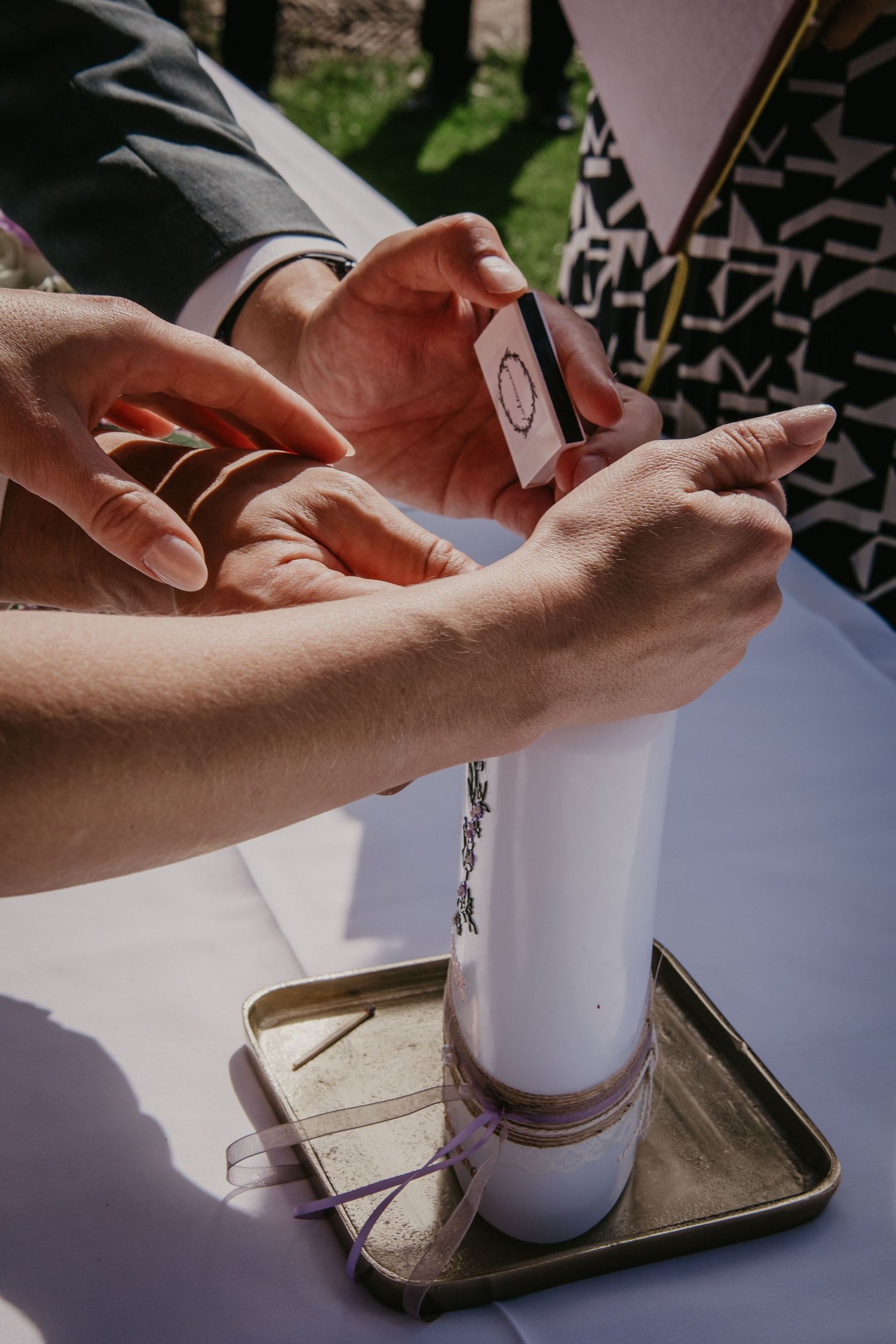 Hands carefully pouring sand into a glass container during a wedding ceremony ritual.