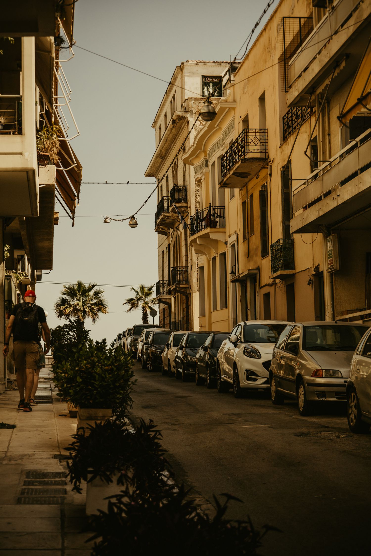 Vintage-toned street scene in Athens with parked cars and traditional architecture.