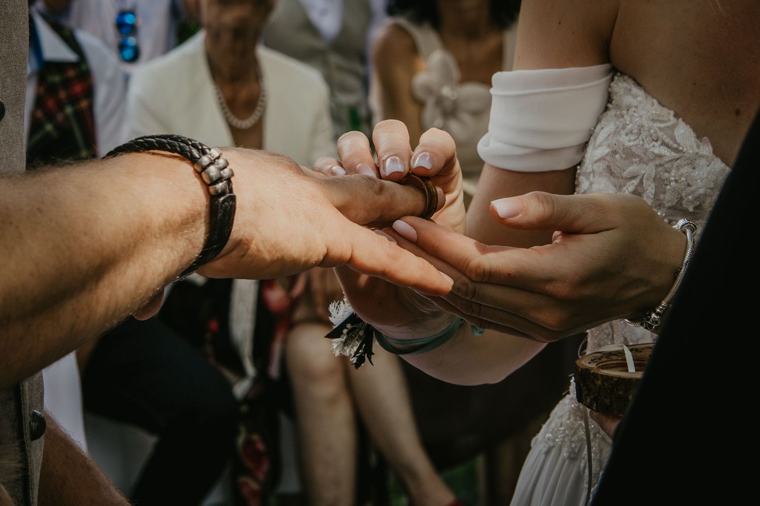 Close-up of hands exchanging rings during an outdoor wedding ceremony, symbolizing love and commitment.