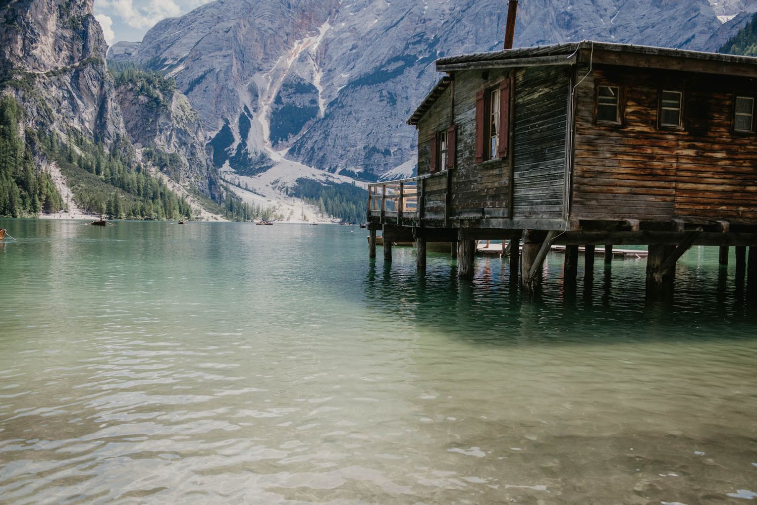 Mountain lake with wooden cabin structures built on stilts over turquoise waters.