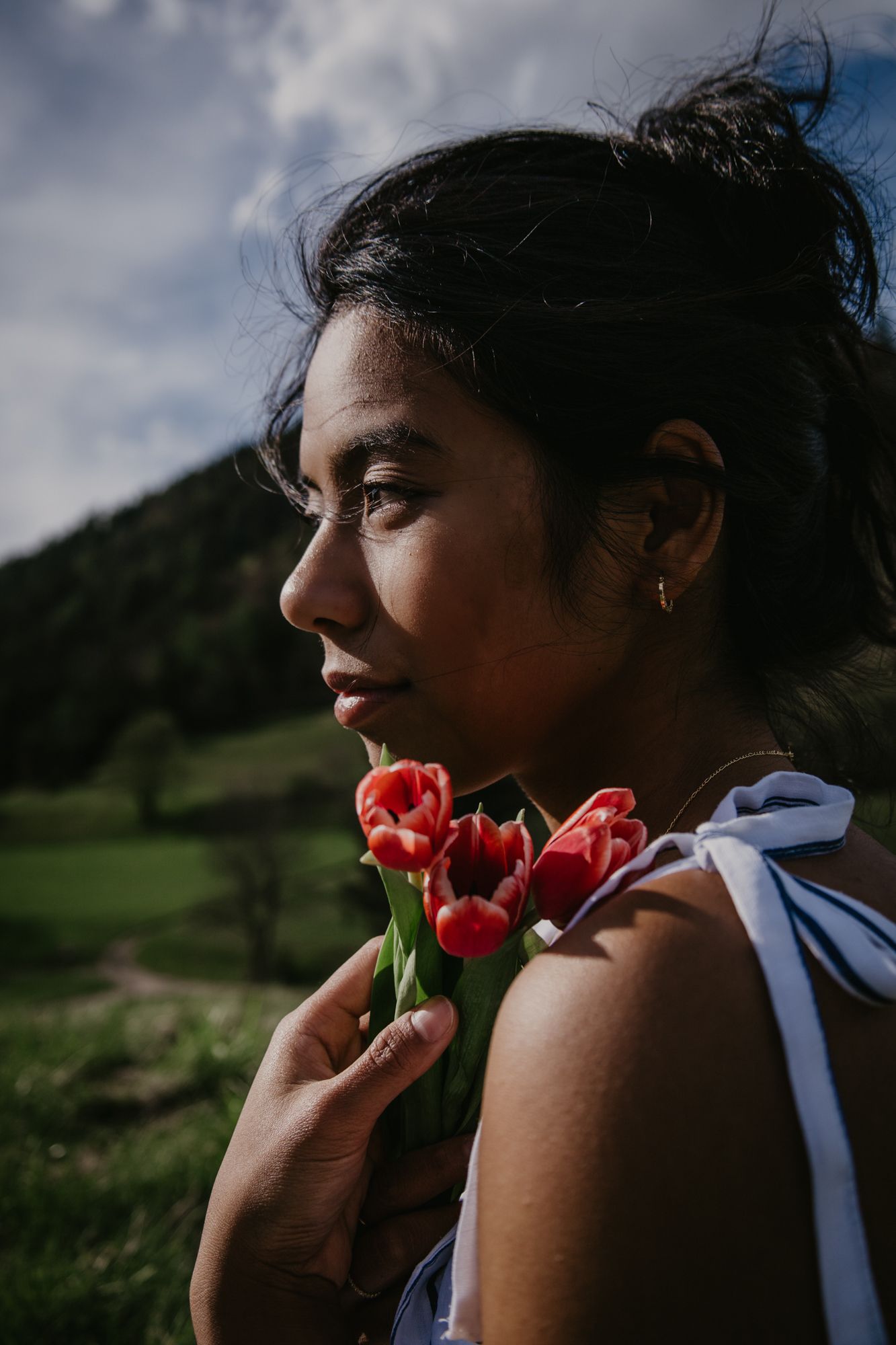 Close-up portrait with red tulips against mountain backdrop.