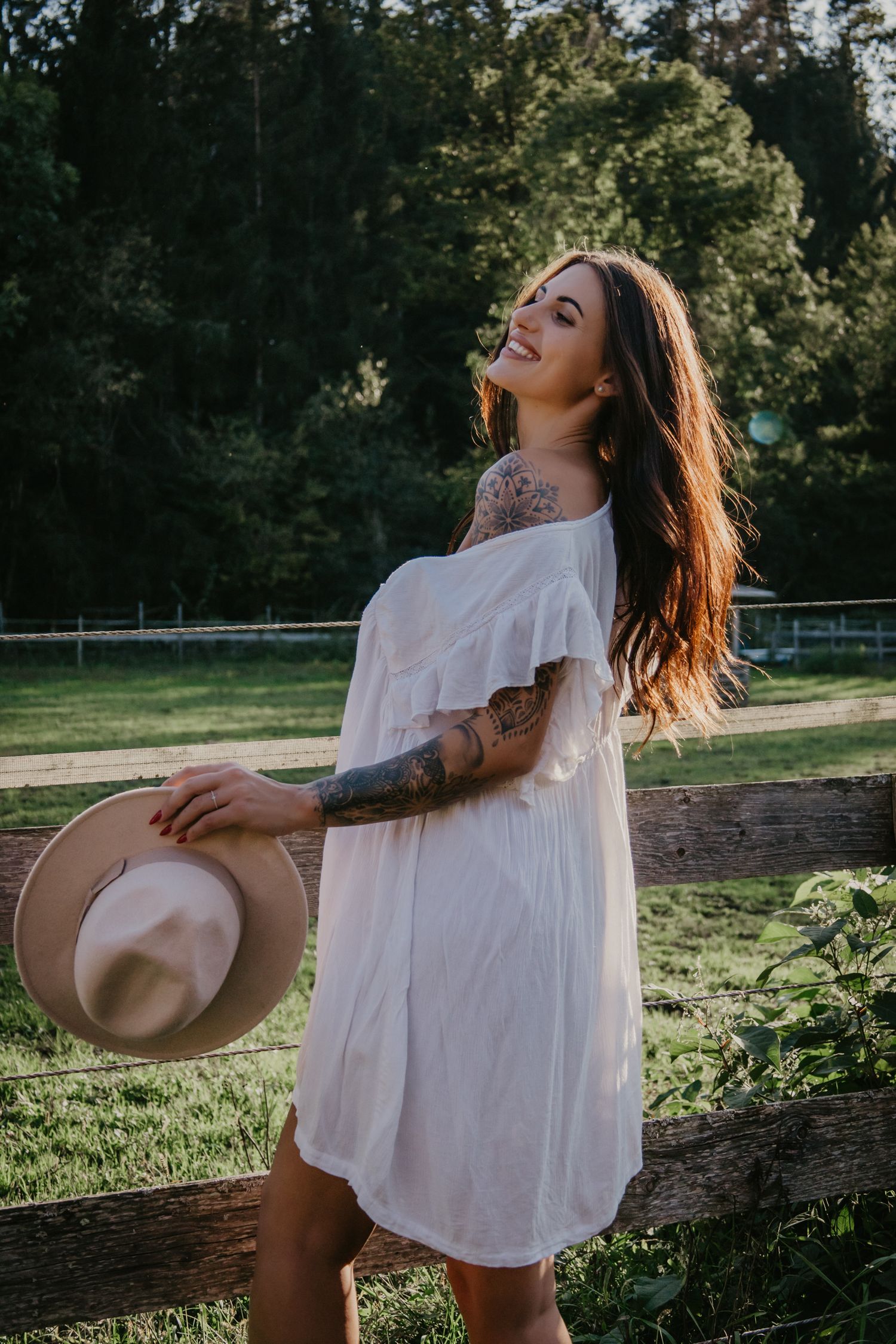 Person in white dress enjoying a sunny day in a grassy field.