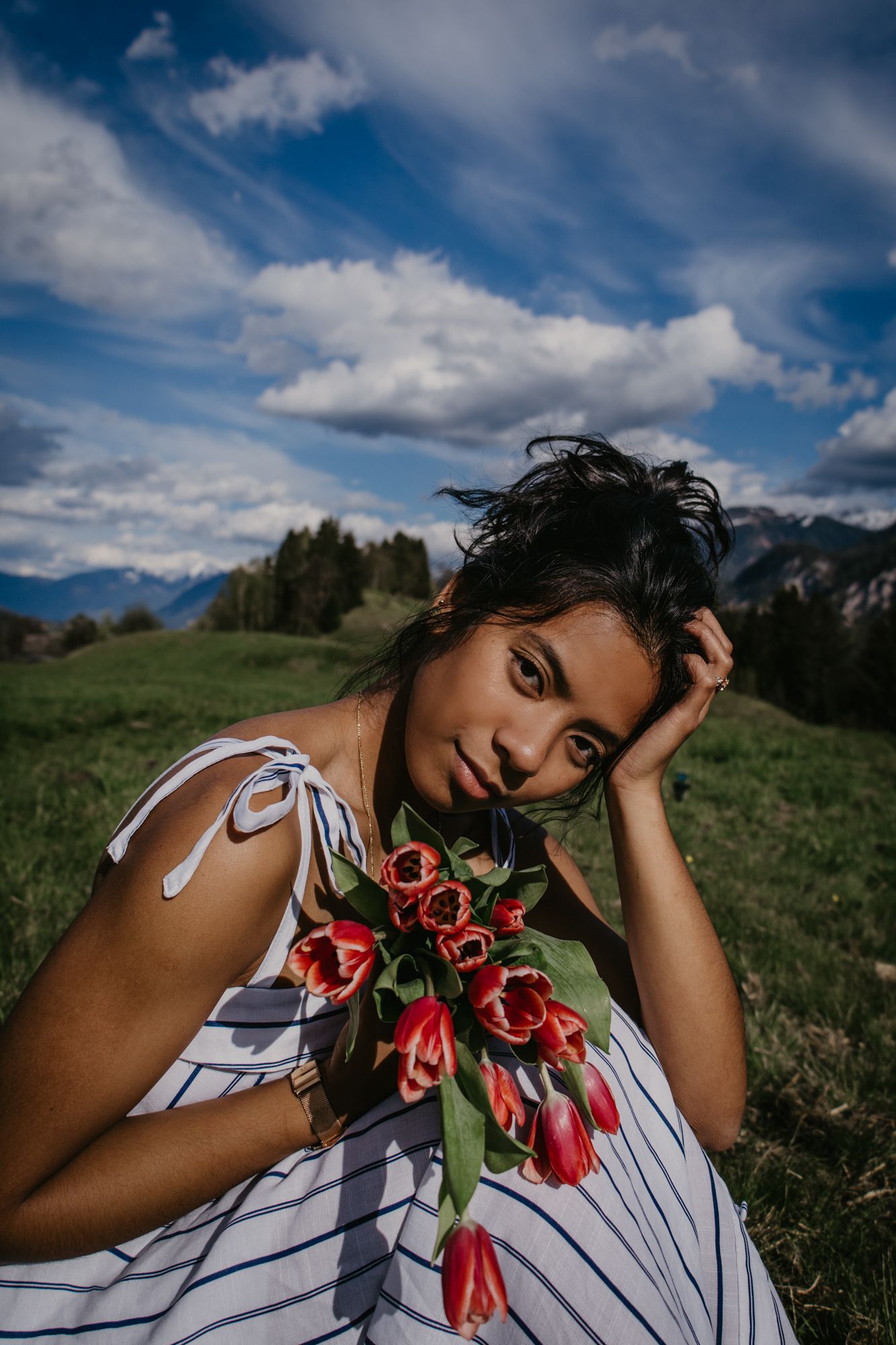 Dreamy mountain photoshoot with striped dress and red tulips.