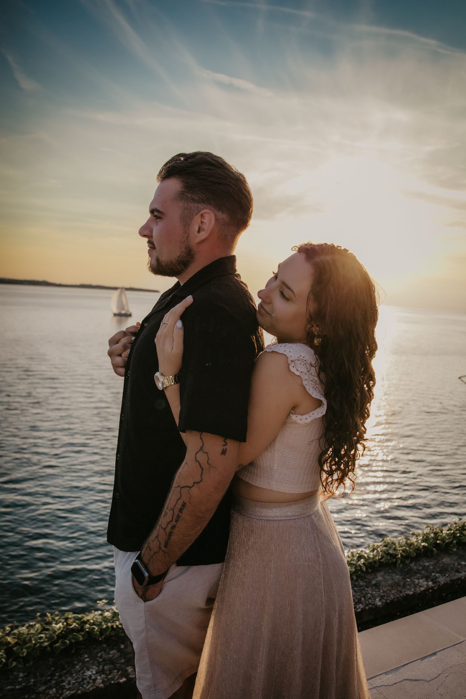 Romantic sunset silhouettes against a waterfront backdrop with warm golden light.