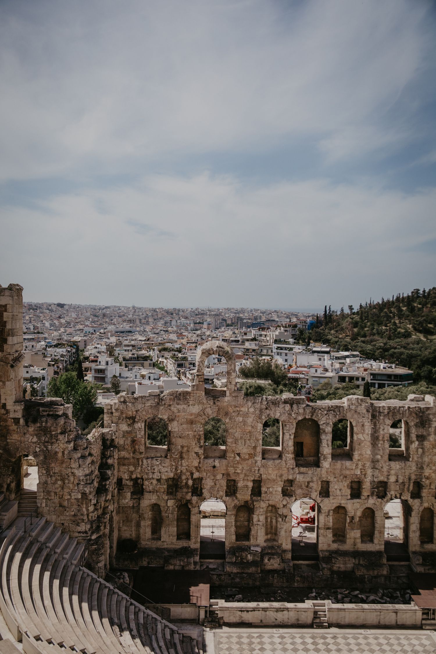 Ancient stone amphitheater ruins overlooking the sprawling city of Athens.