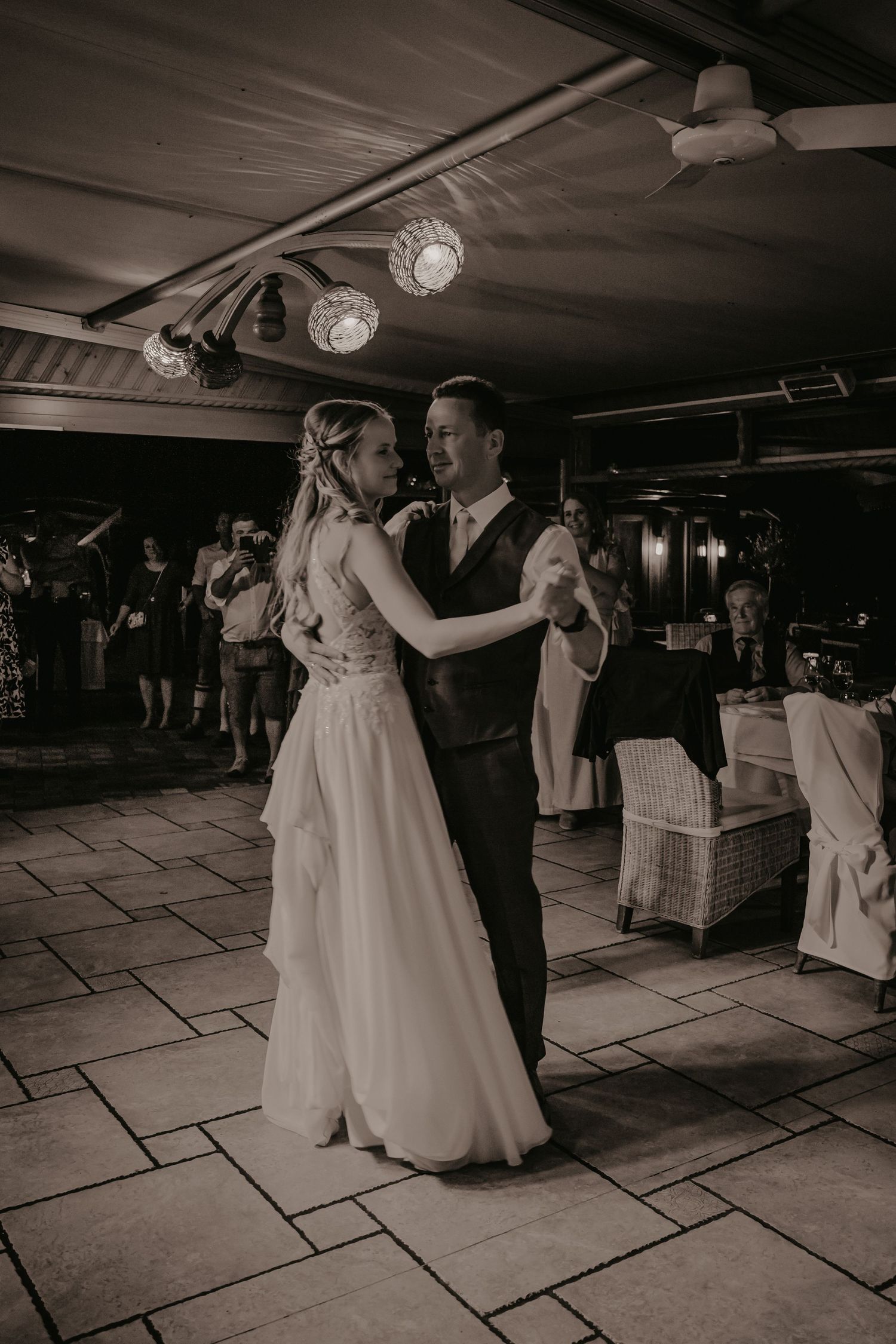 A couple dancing together at their wedding reception in an elegantly lit venue.