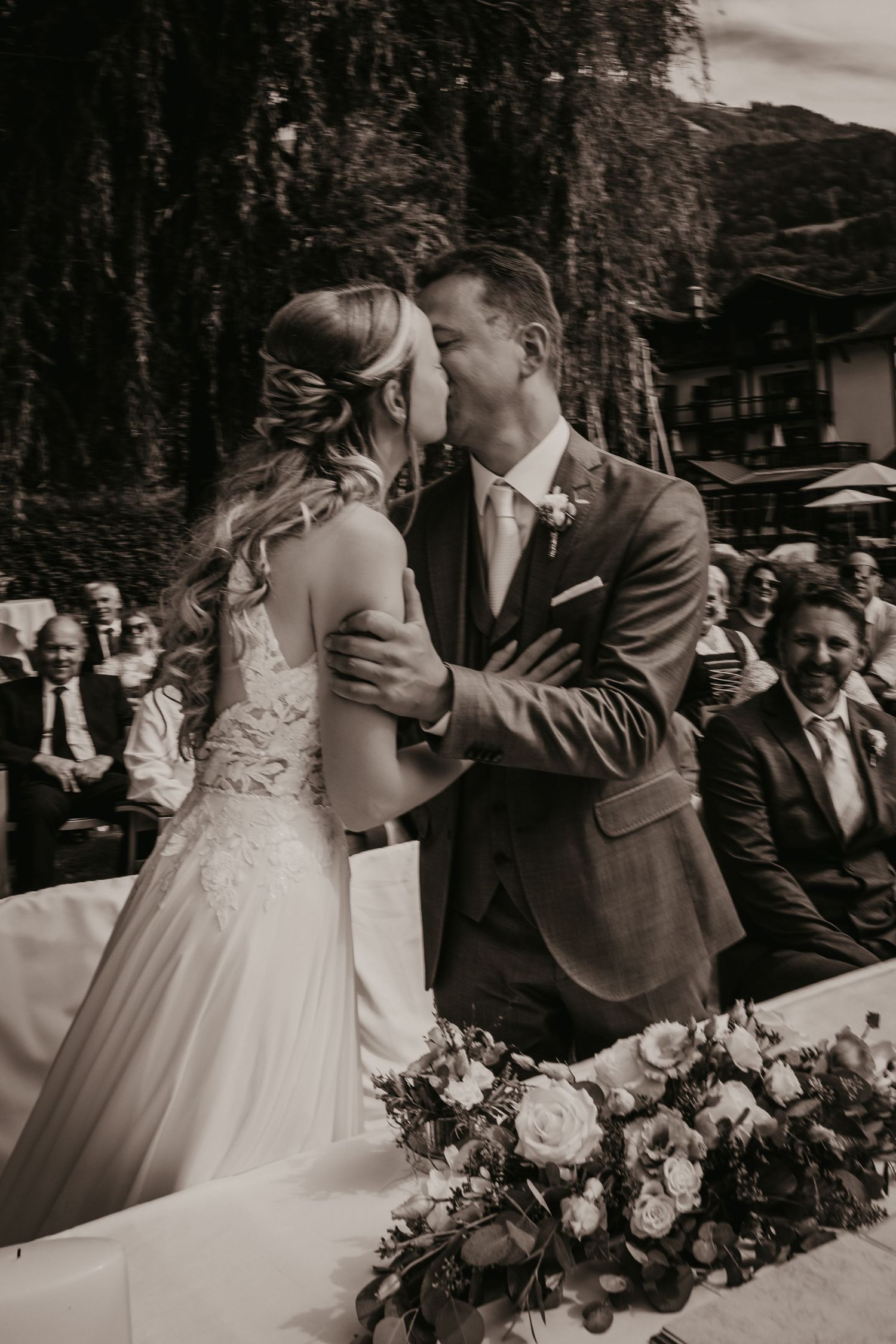 Black and white wedding ceremony photo with floral decorations in foreground.
