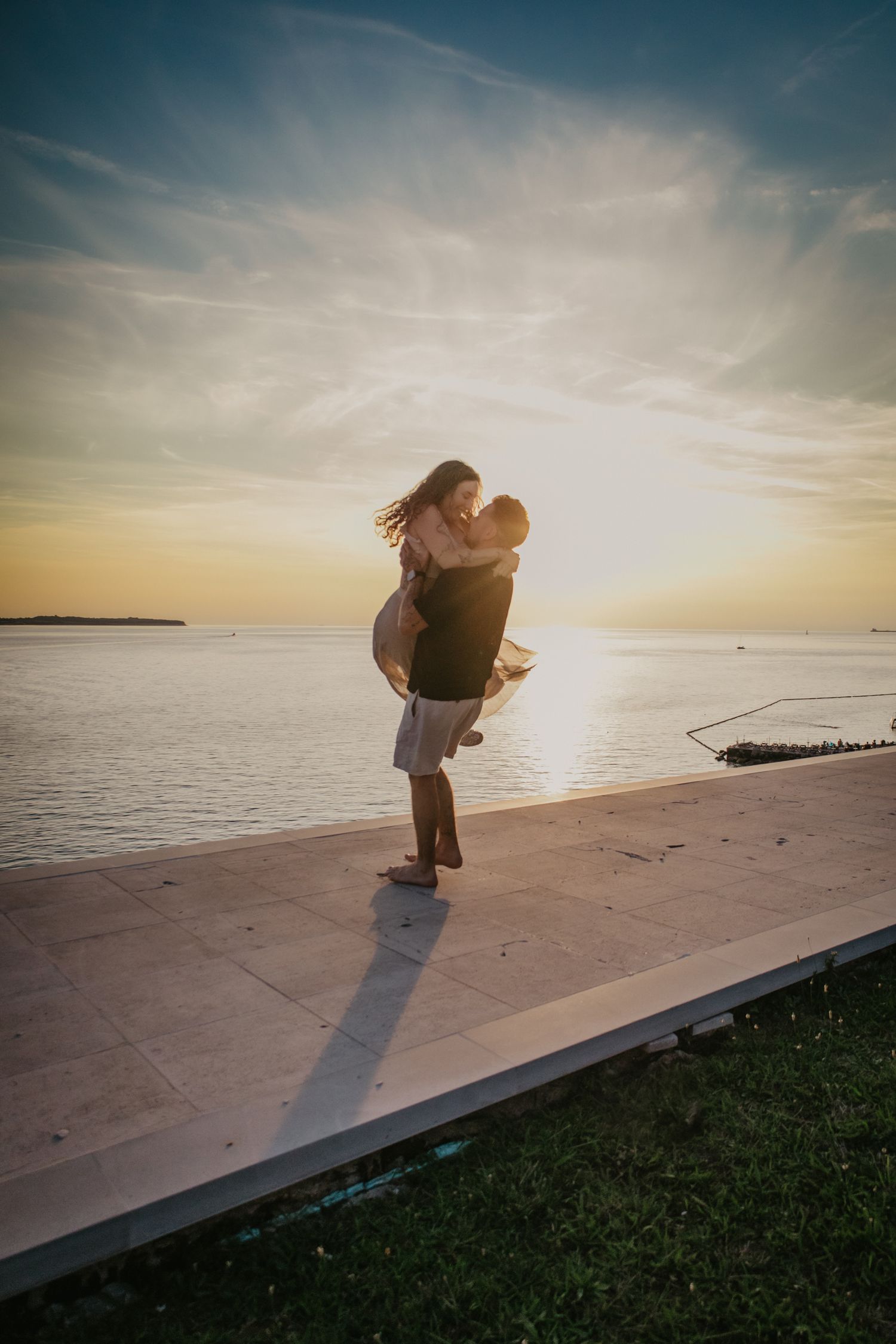 Dramatic seaside portraits with couple silhouetted against golden sunset sky.