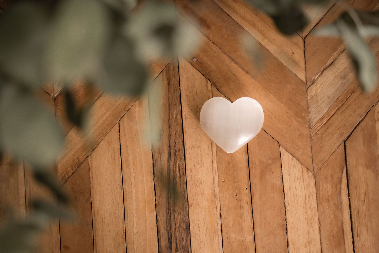 A rustic wooden fence with a small white heart-shaped decoration mounted on one of its panels.