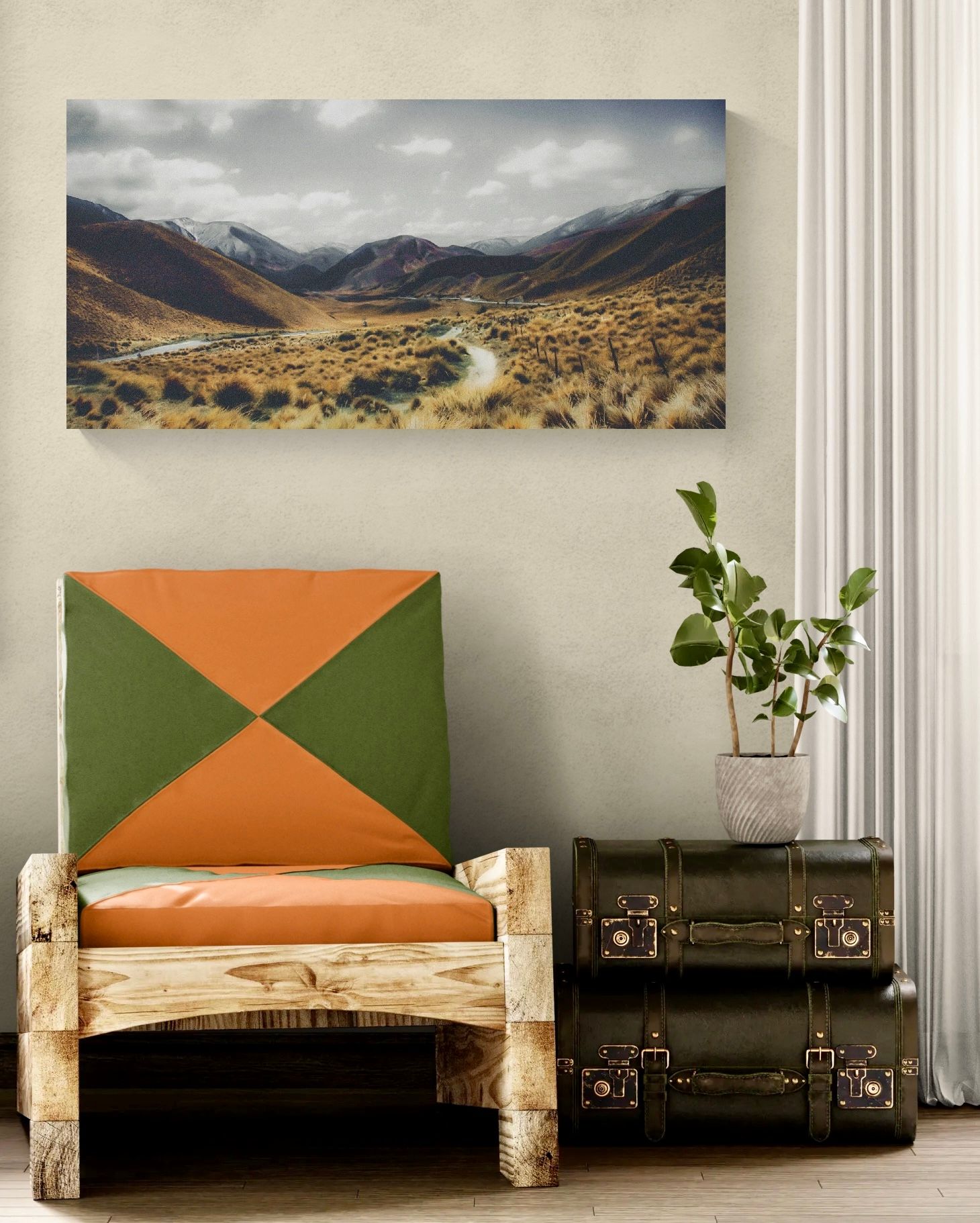 Rustic wooden chair with orange and green geometric cushion beside vintage trunks under a mountain landscape canvas.