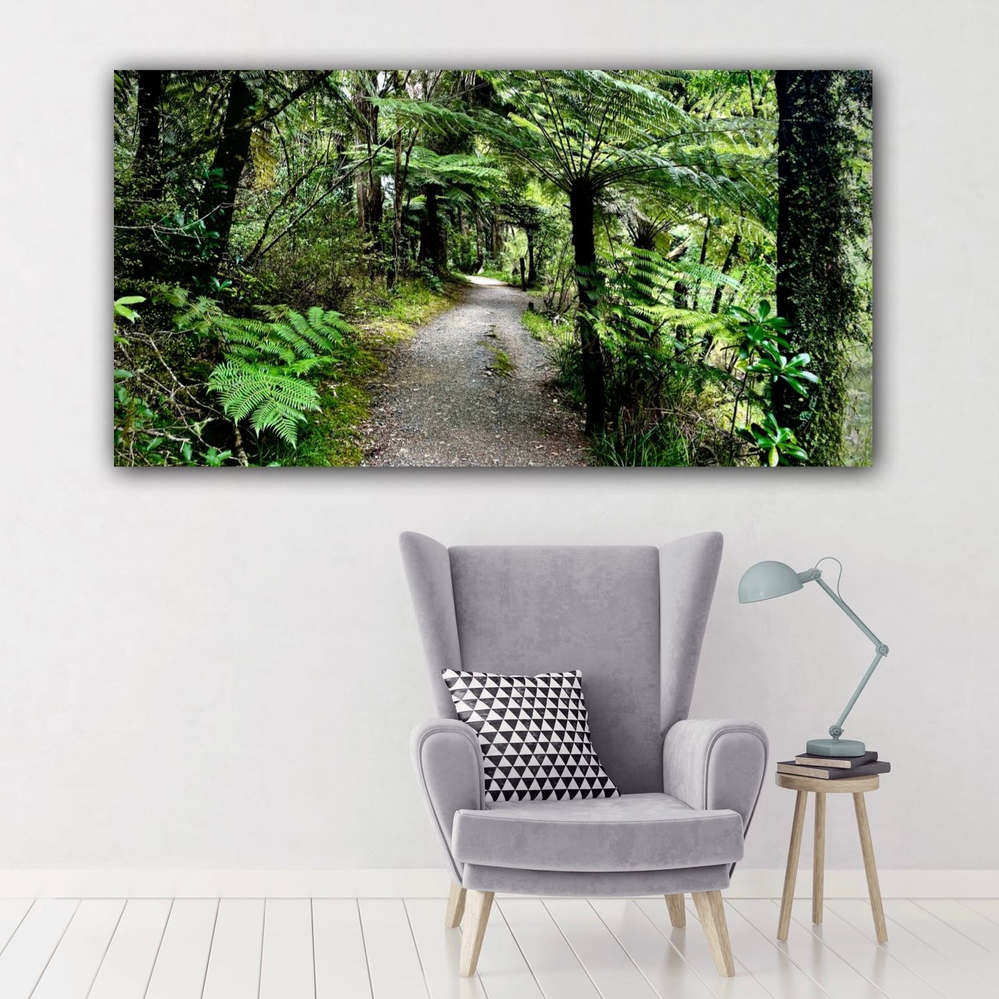 Canvas wall art of a lush green forest path with ferns and trees, displayed above a gray armchair in a modern living room.