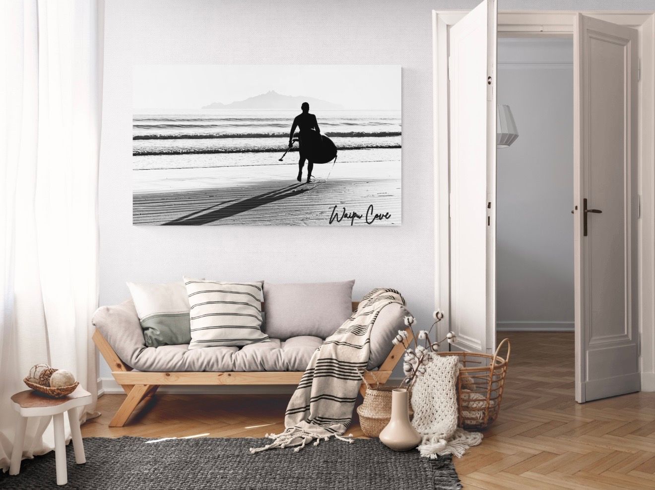 Black and white surfer silhouette canvas art displayed above a wooden bench in a bright minimalist living room.