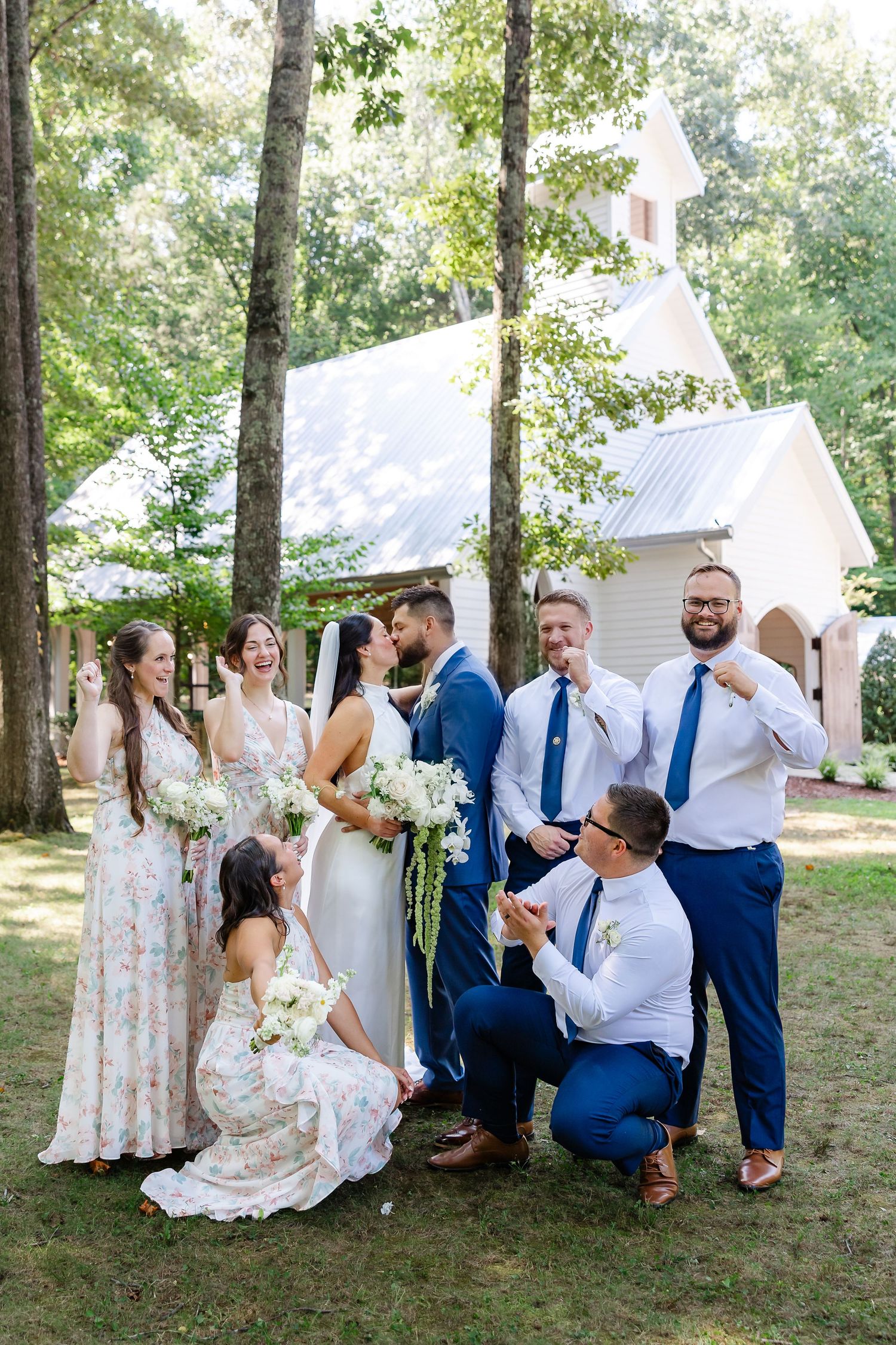 Wedding party poses outside a white chapel surrounded by trees at firefly lane in Dickson, tn