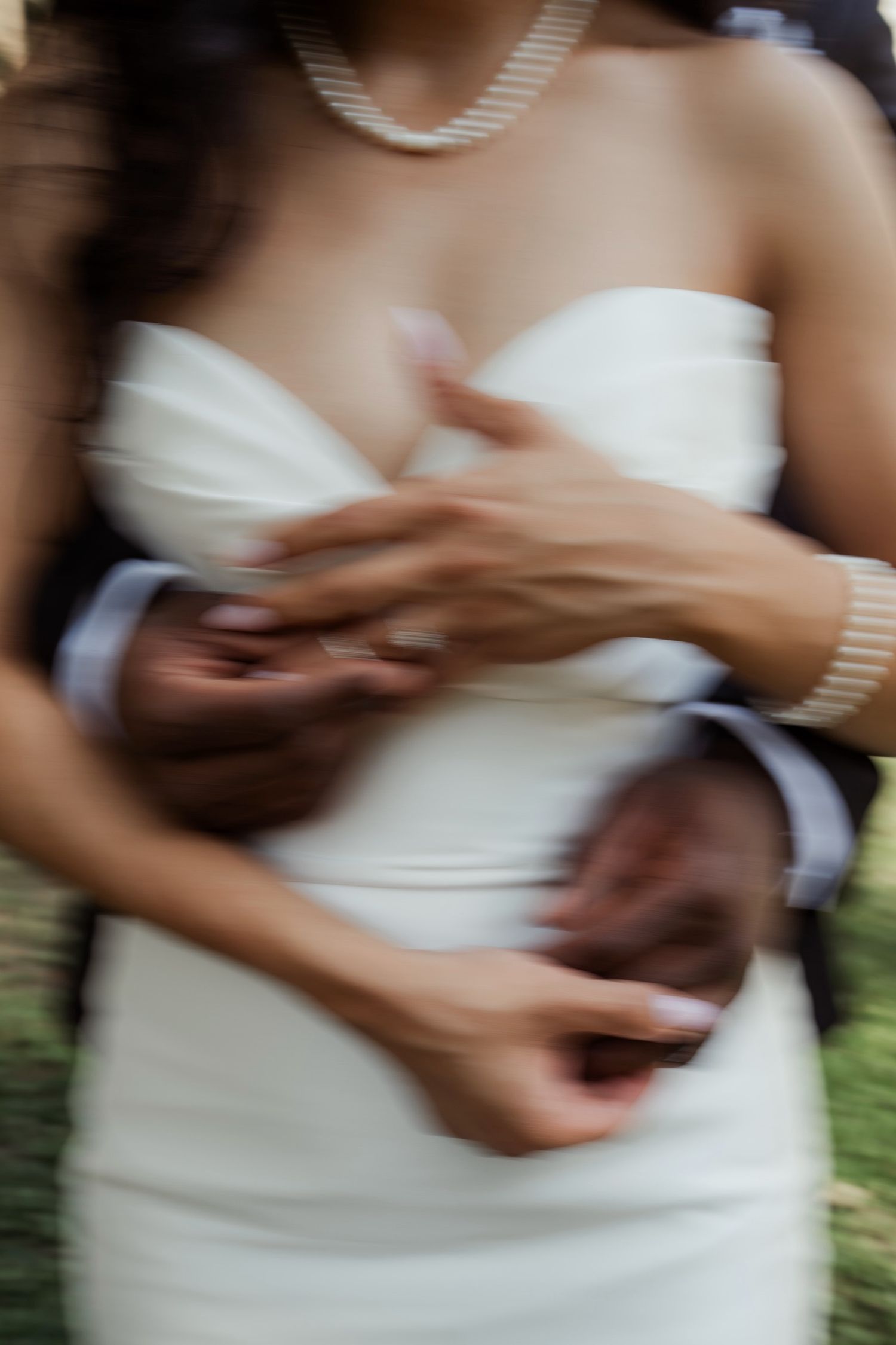 Bride in strapless gown with pearl necklace embraced by groom in suit, motion blur wedding photo at Firefly Lane Chapel Dickson Tennessee
