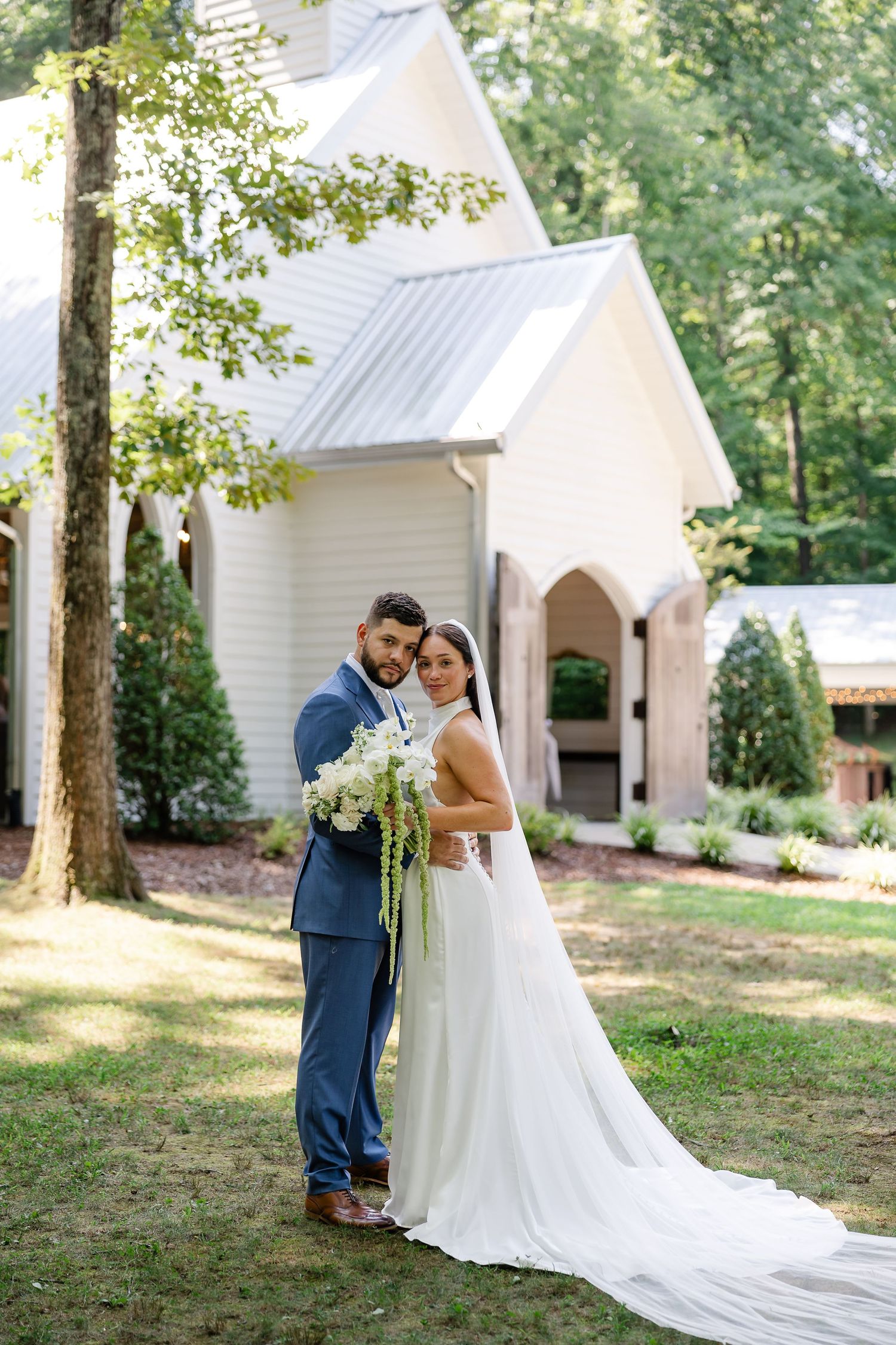 Bride and groom embracing outdoors in front of a white chapel at firefly lane in Dickson, tn