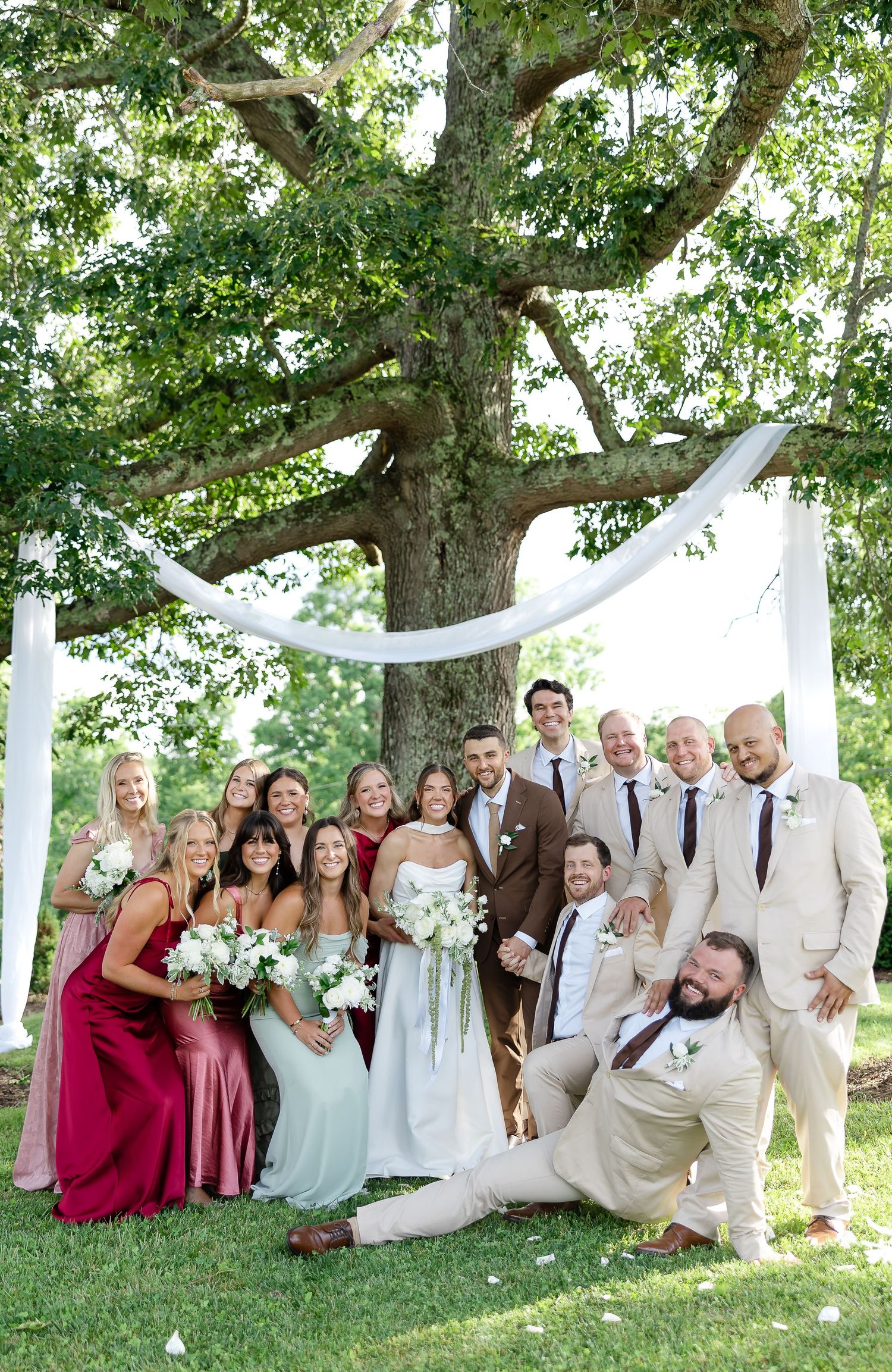 Wedding party posing under a large oak treeat front porch farms, in Charlotte tennessee