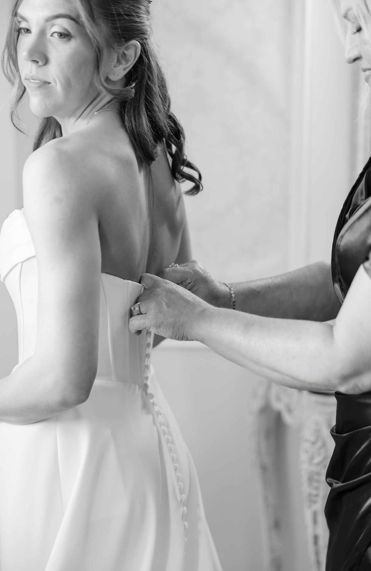 Black and white photo of a bride having her wedding dress buttoned up at front porch farms in Charlotte TN