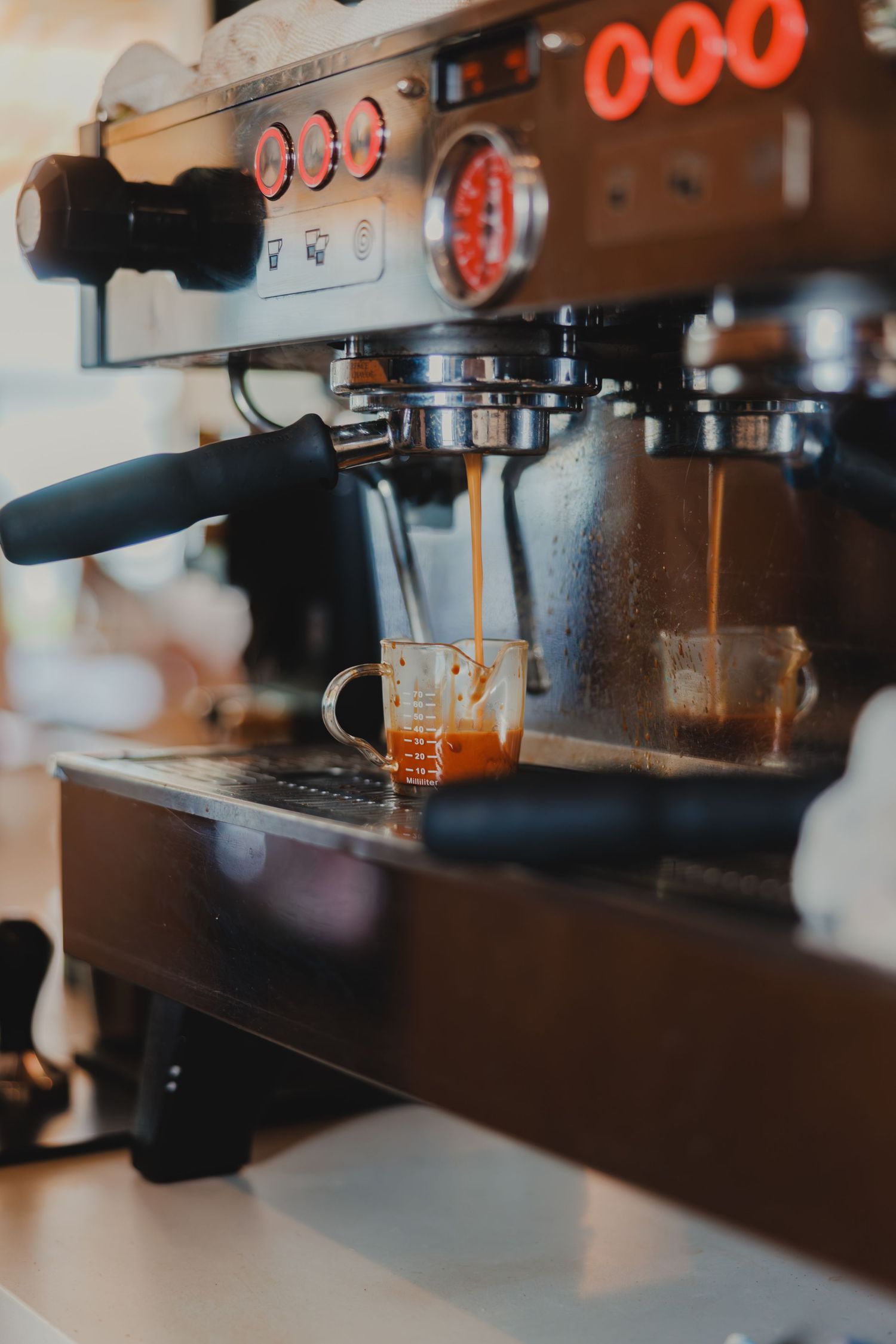 Professional espresso machine brewing fresh shots of espresso into clear glass cups at a cafe.