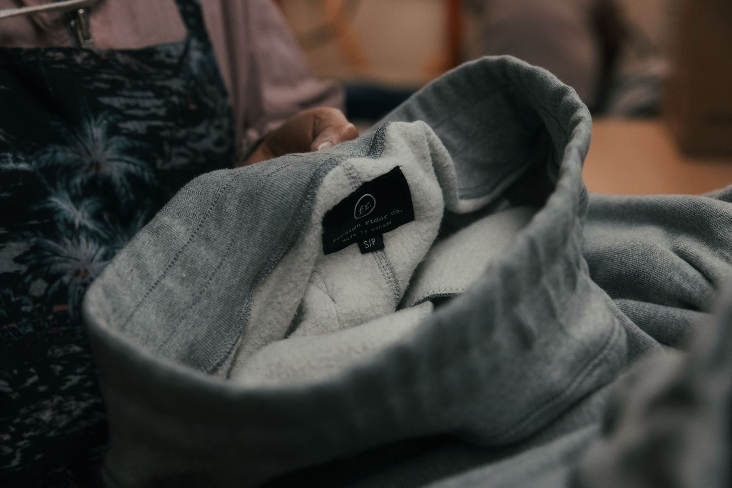 Close-up of a folded gray sweater with a black label, showcasing soft fabric texture and casual style.