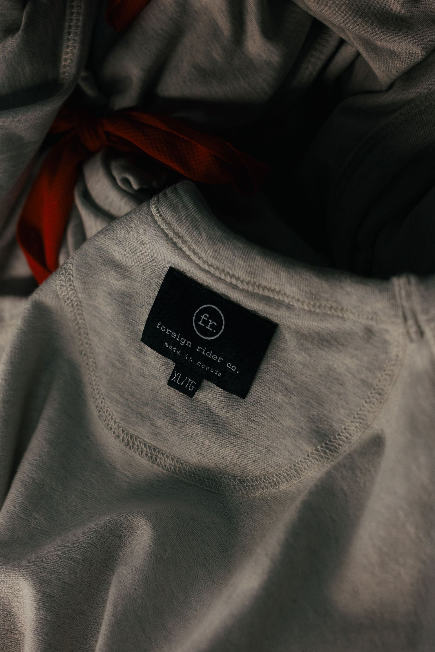 Close-up of a gray Foreign Rider Co. made in Canada clothing label on a heather gray XL garment.