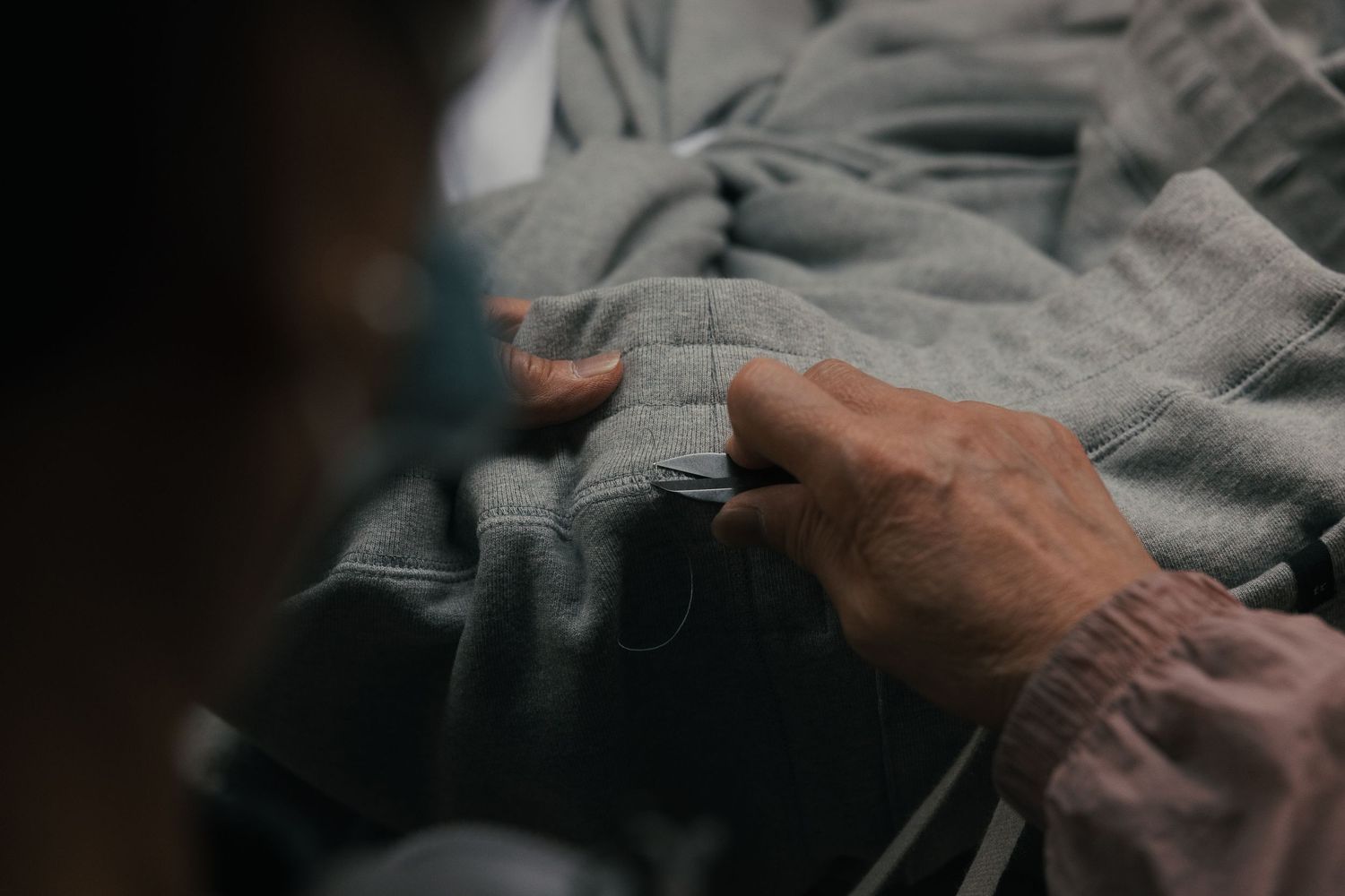 Close-up of hands carefully examining gray fabric texture, showcasing artisan craftsmanship and textile quality.