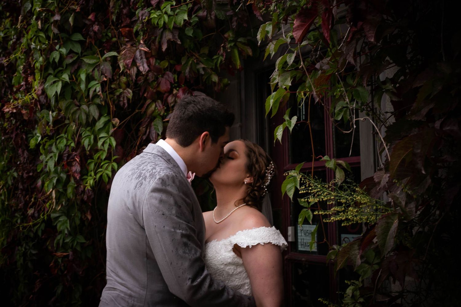 A tender moment between newlyweds against a backdrop of climbing vines.