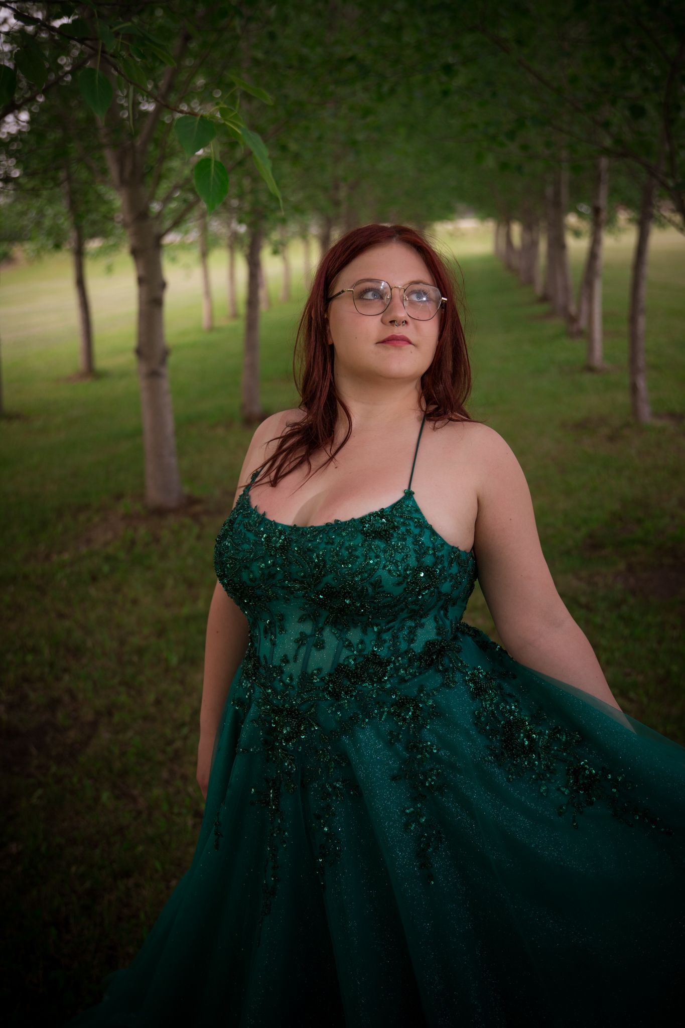 Emerald evening gown photographed in wooded park setting with natural lighting.