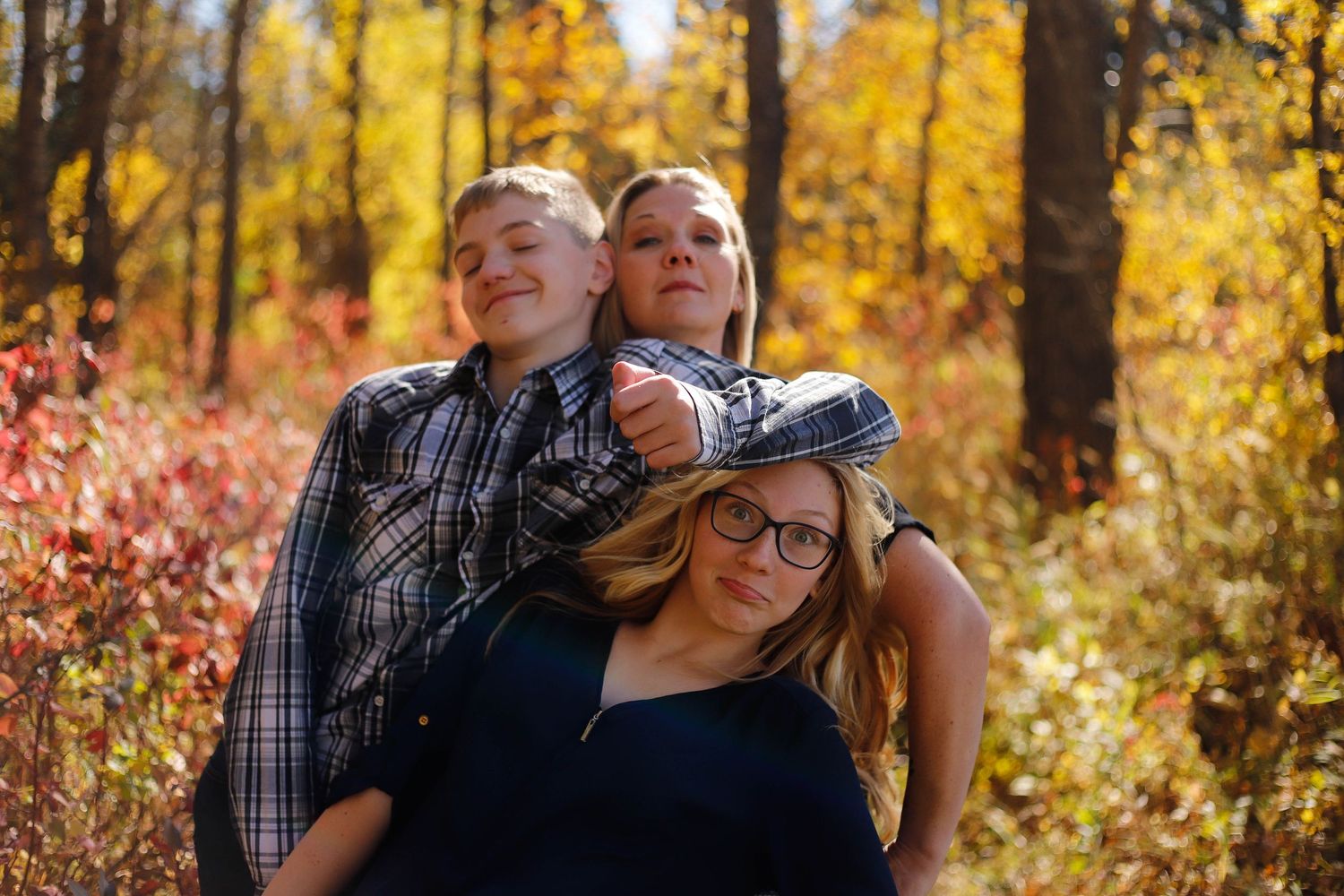 Autumn family photoshoot with vibrant yellow foliage in the background during golden hour.