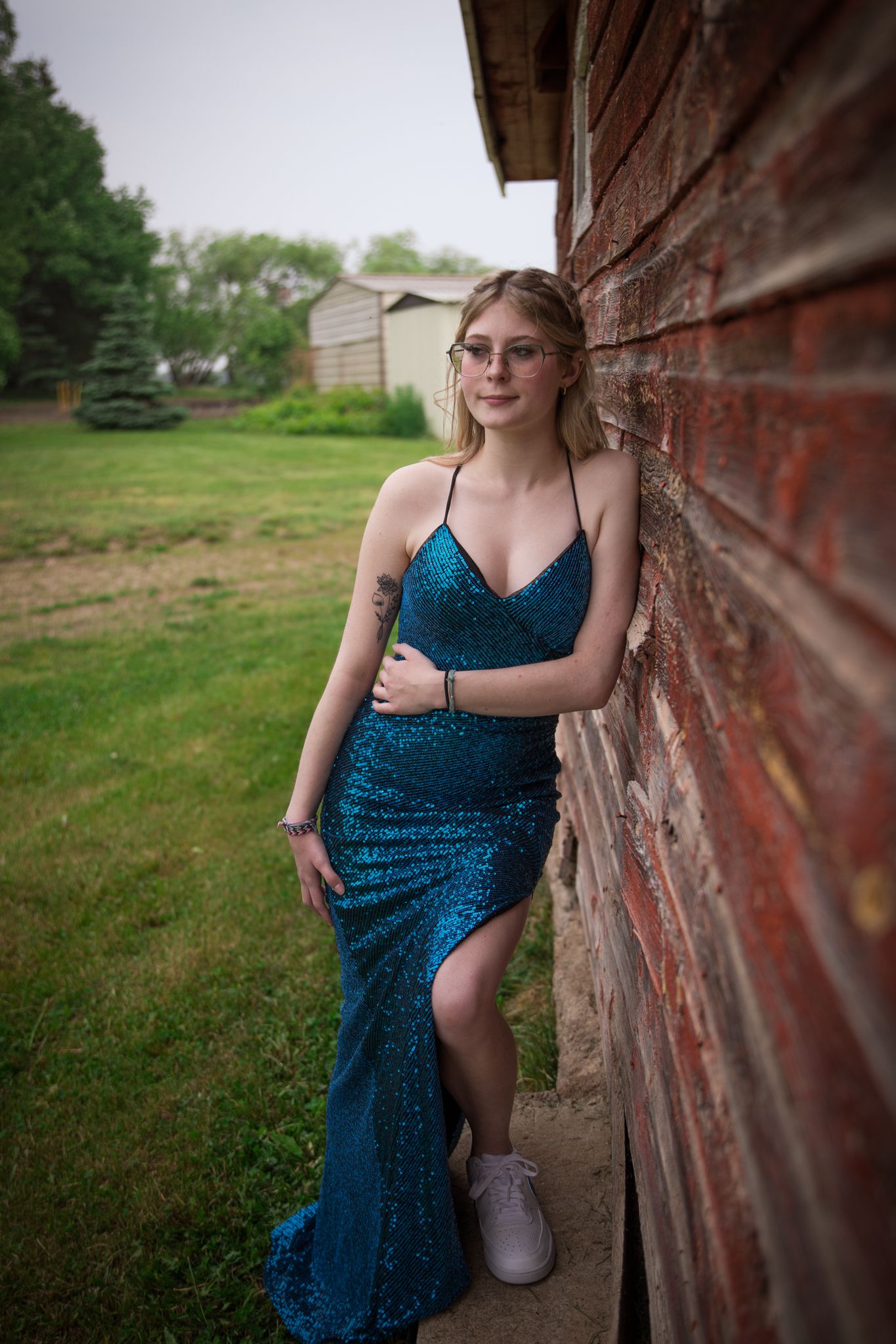 A sequined teal gown sparkles in natural light against weathered red brick.