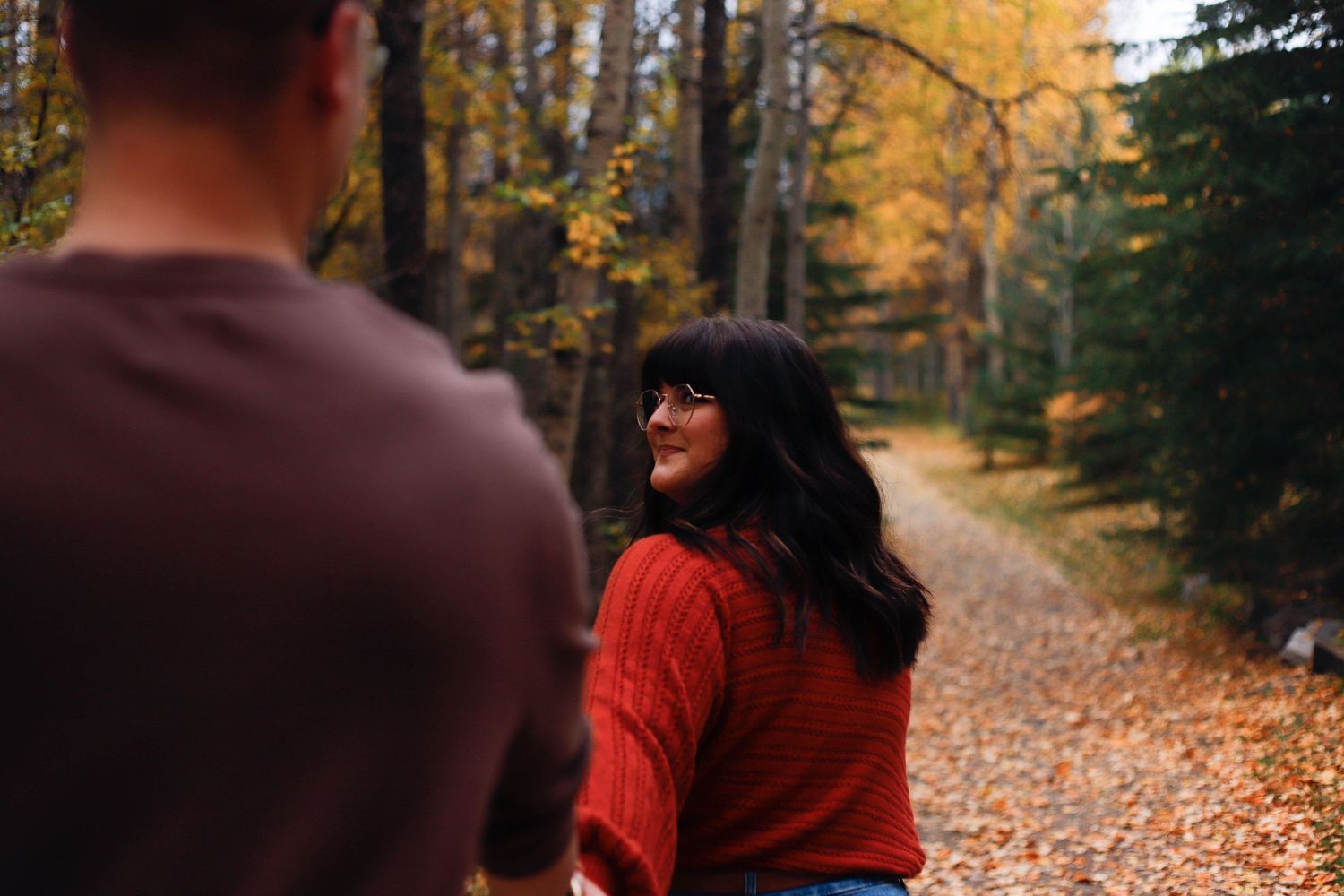 A romantic fall photoshoot on a rustic bridge with colorful autumn leaves in the background.