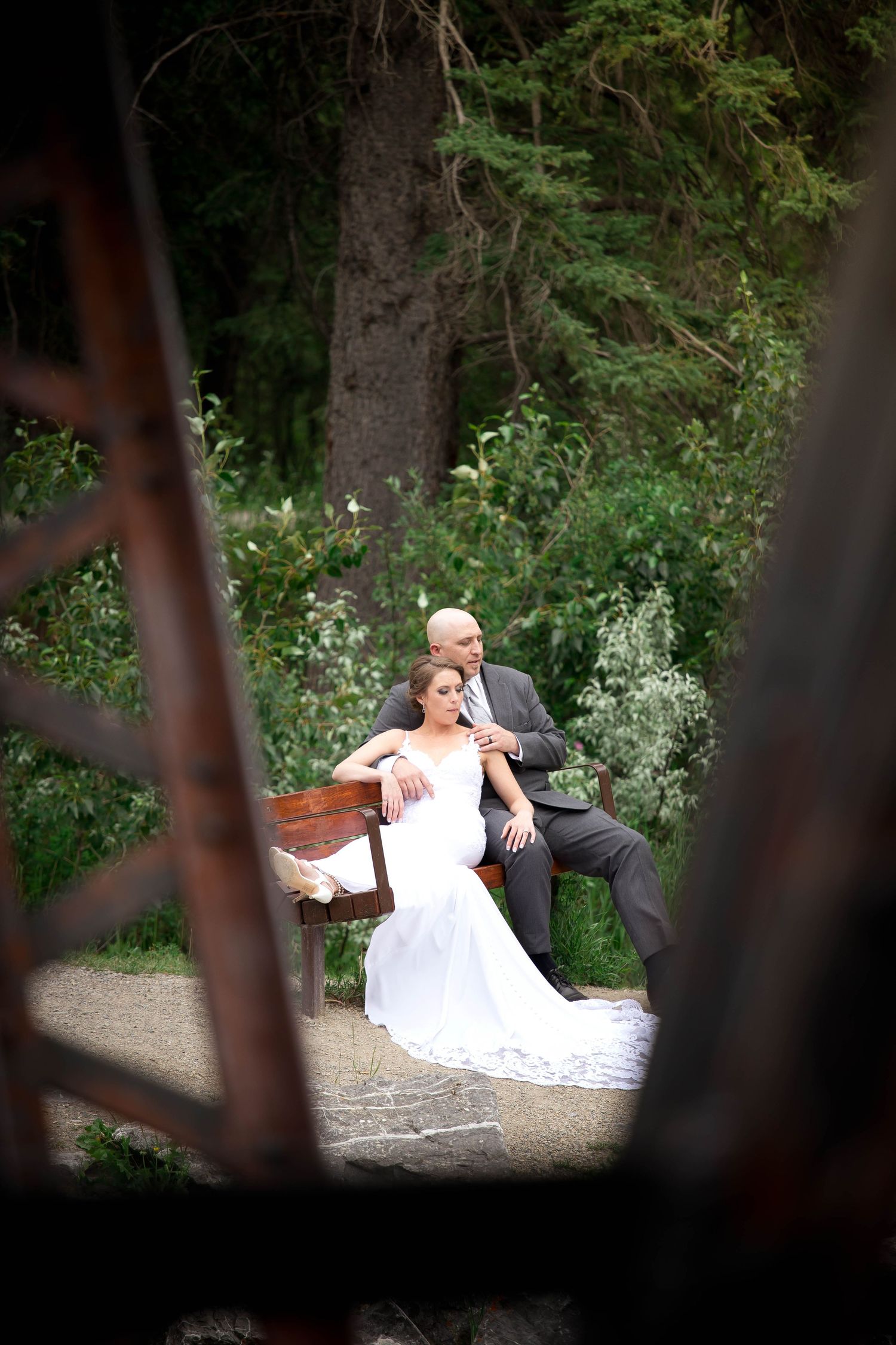 Wedding couple posing on stone steps surrounded by lush greenery and gardens.