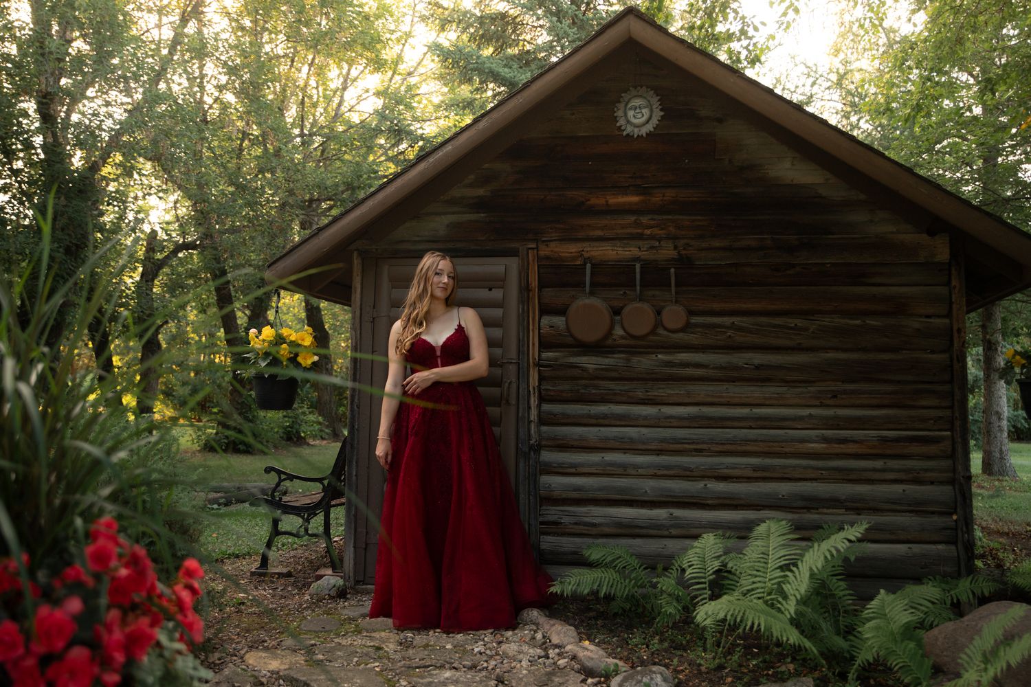 A rustic log cabin surrounded by trees in golden evening light.