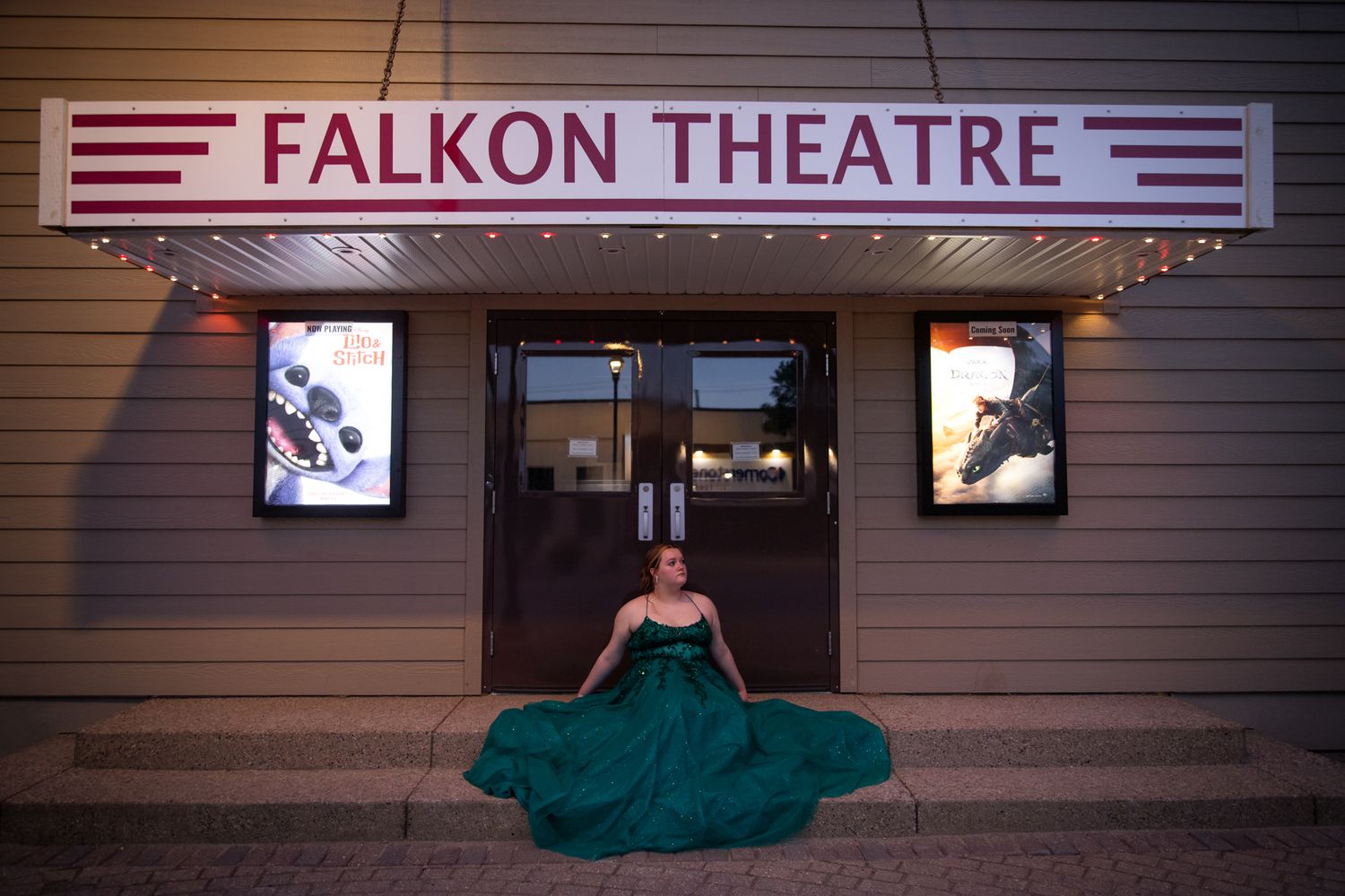 A flowing green formal dress spreads across the steps of the Falkon Theatre entrance.