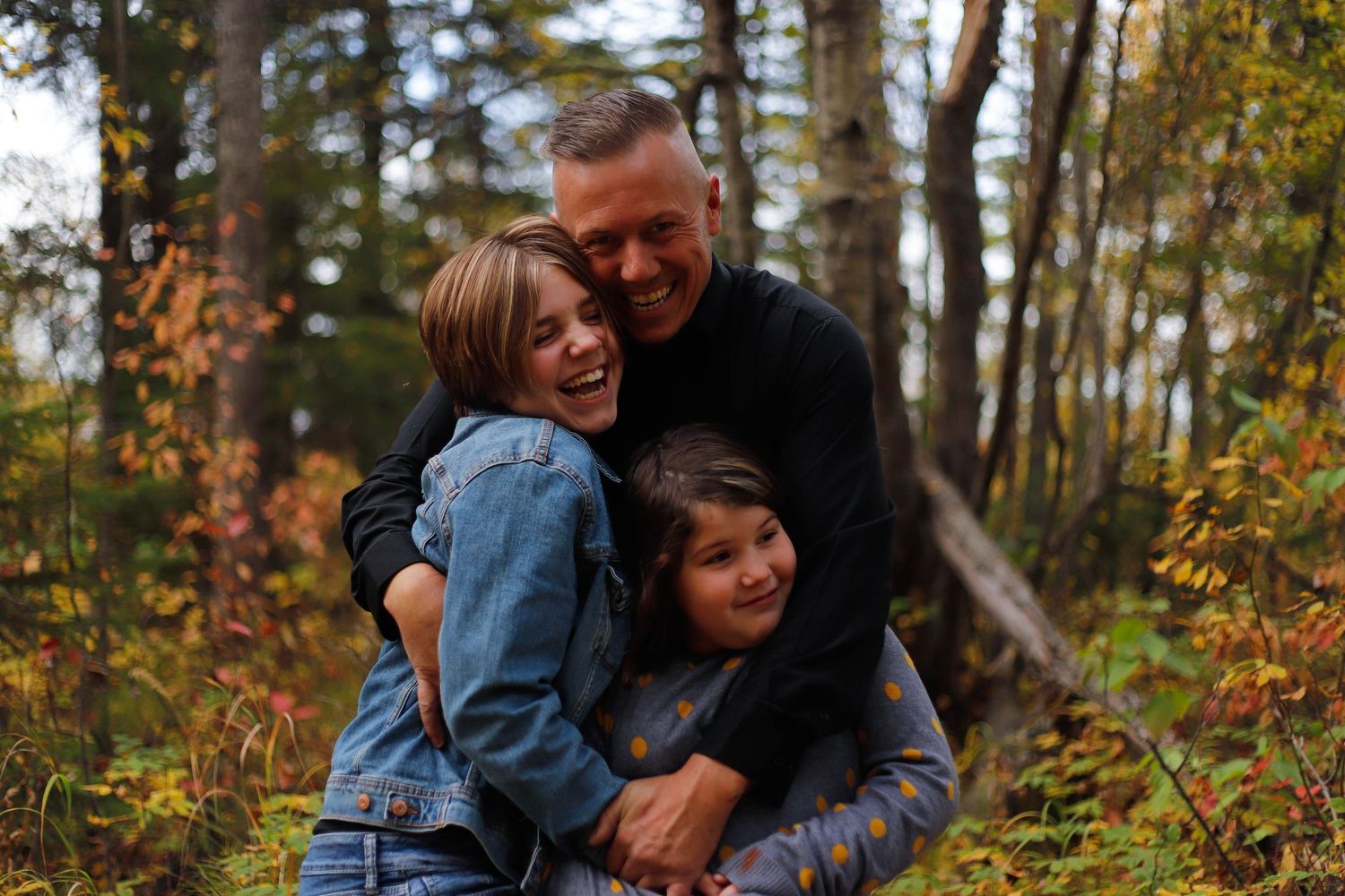 A joyful embrace captured in a wooded setting during autumn.